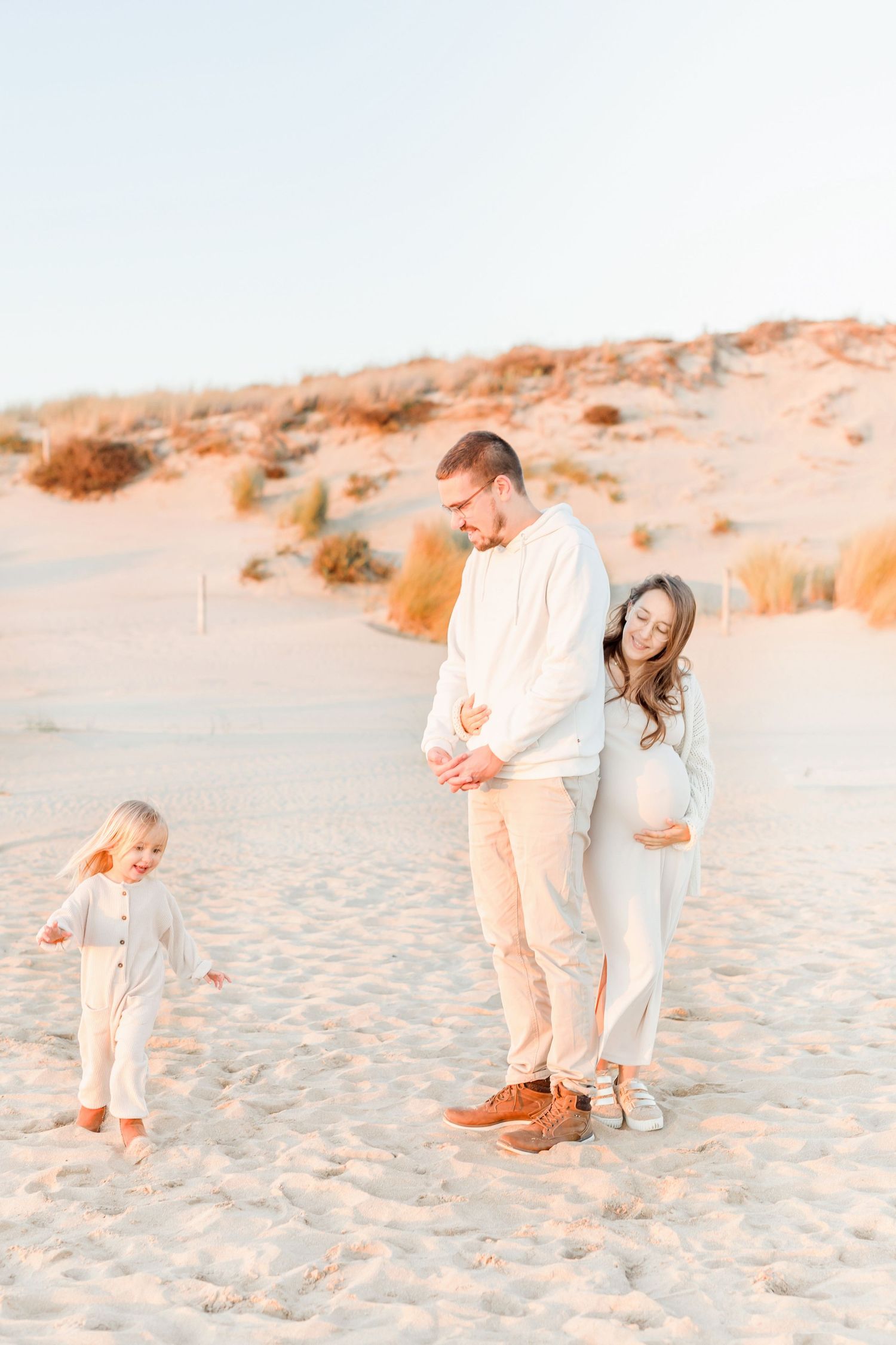 A family enjoys playful moments together on a sandy beach during sunset.