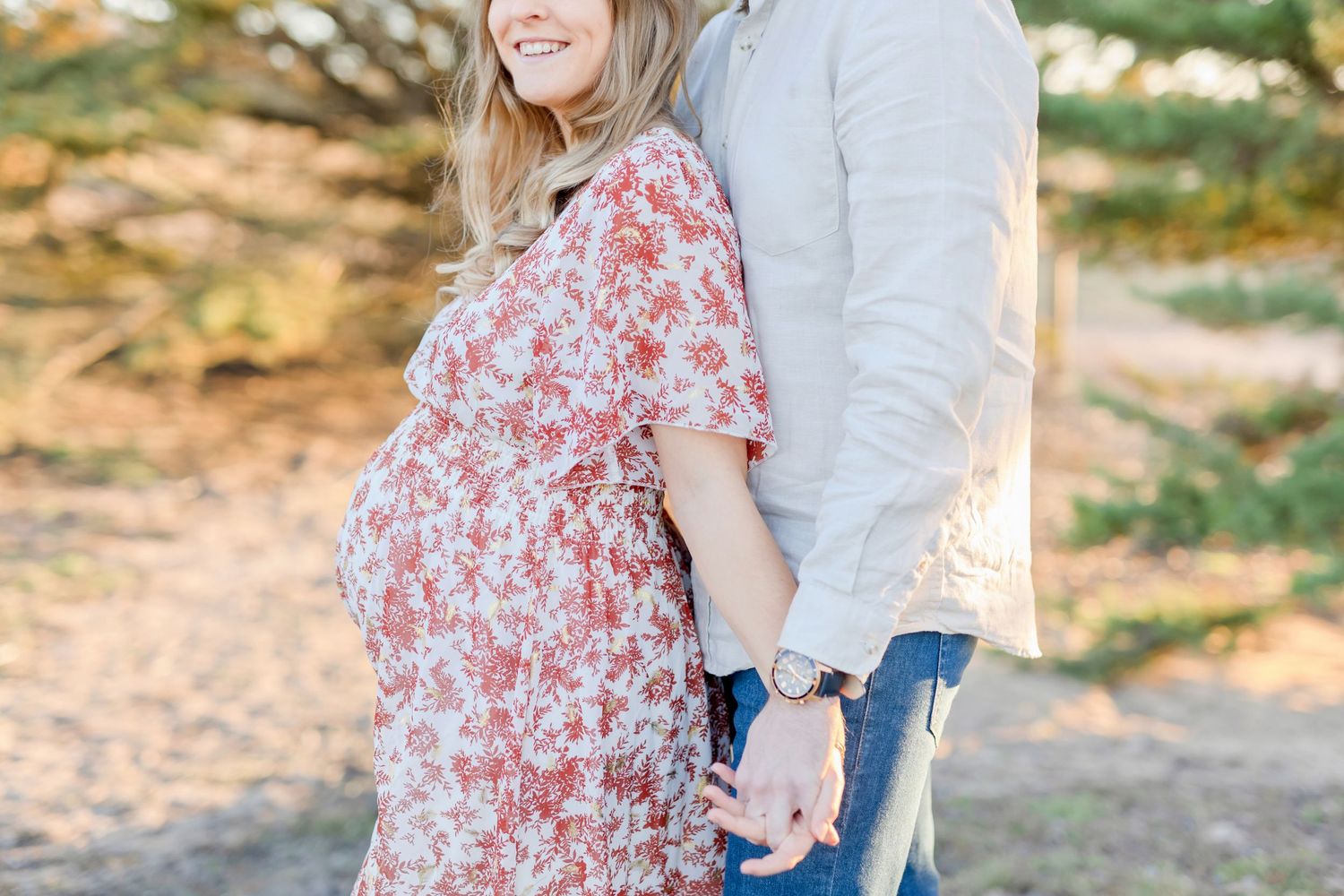 Close-up maternity photo showing couple's embrace on nature path.