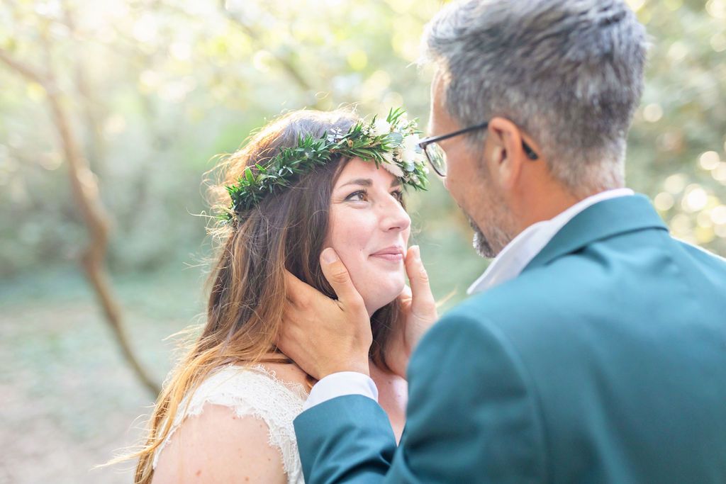 Intimate wedding portrait in dappled sunlight with gentle touch and floral crown.