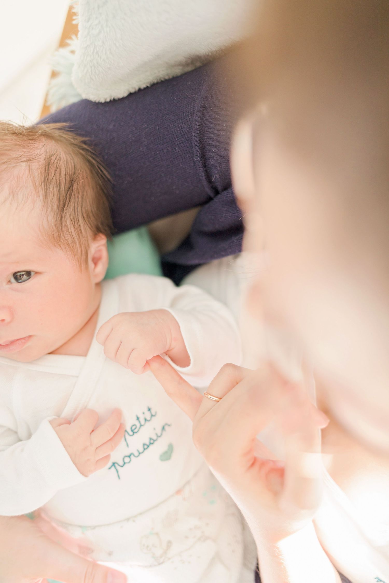 Close-up of baby on changing table with caregiver nearby.