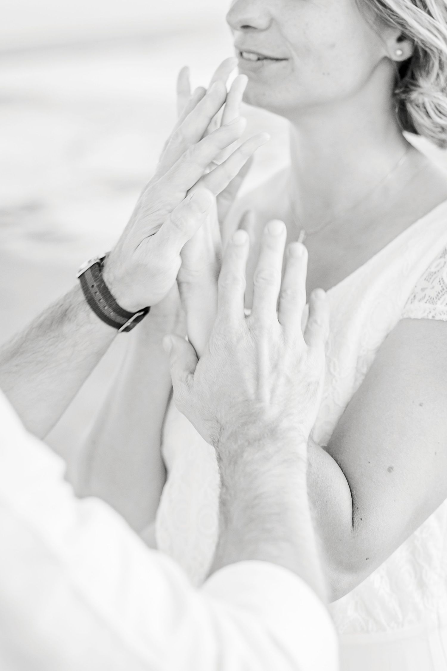 Gentle hands touching in an intimate black and white moment wearing white lace and a bracelet.