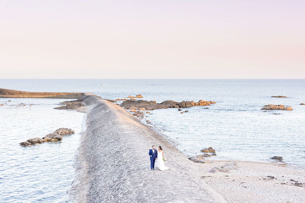 Panoramic view of a coastal wedding setting with rocky outcrops and calm waters.