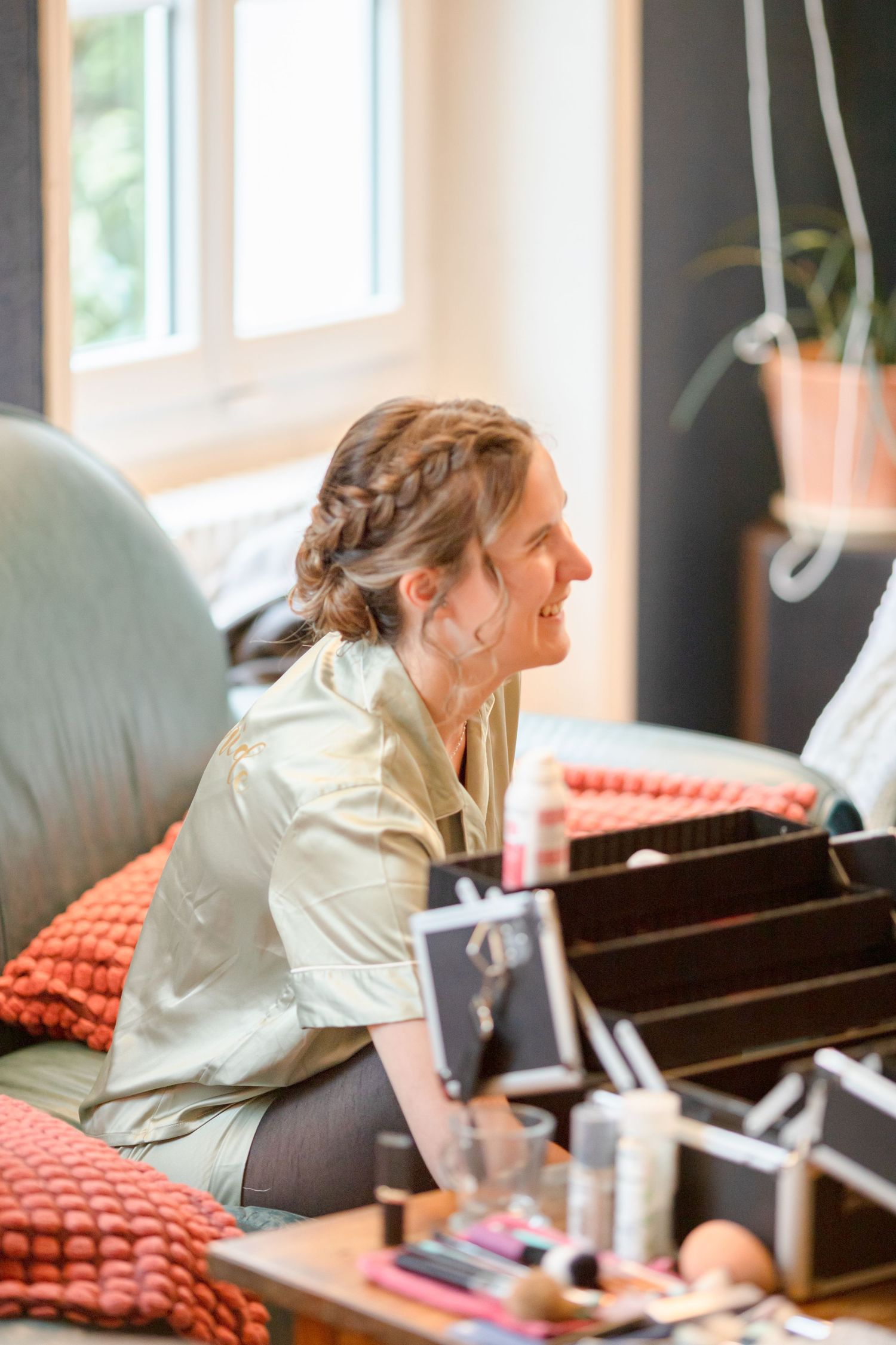 Side profile shots of someone getting their makeup done while seated in a light-filled room.