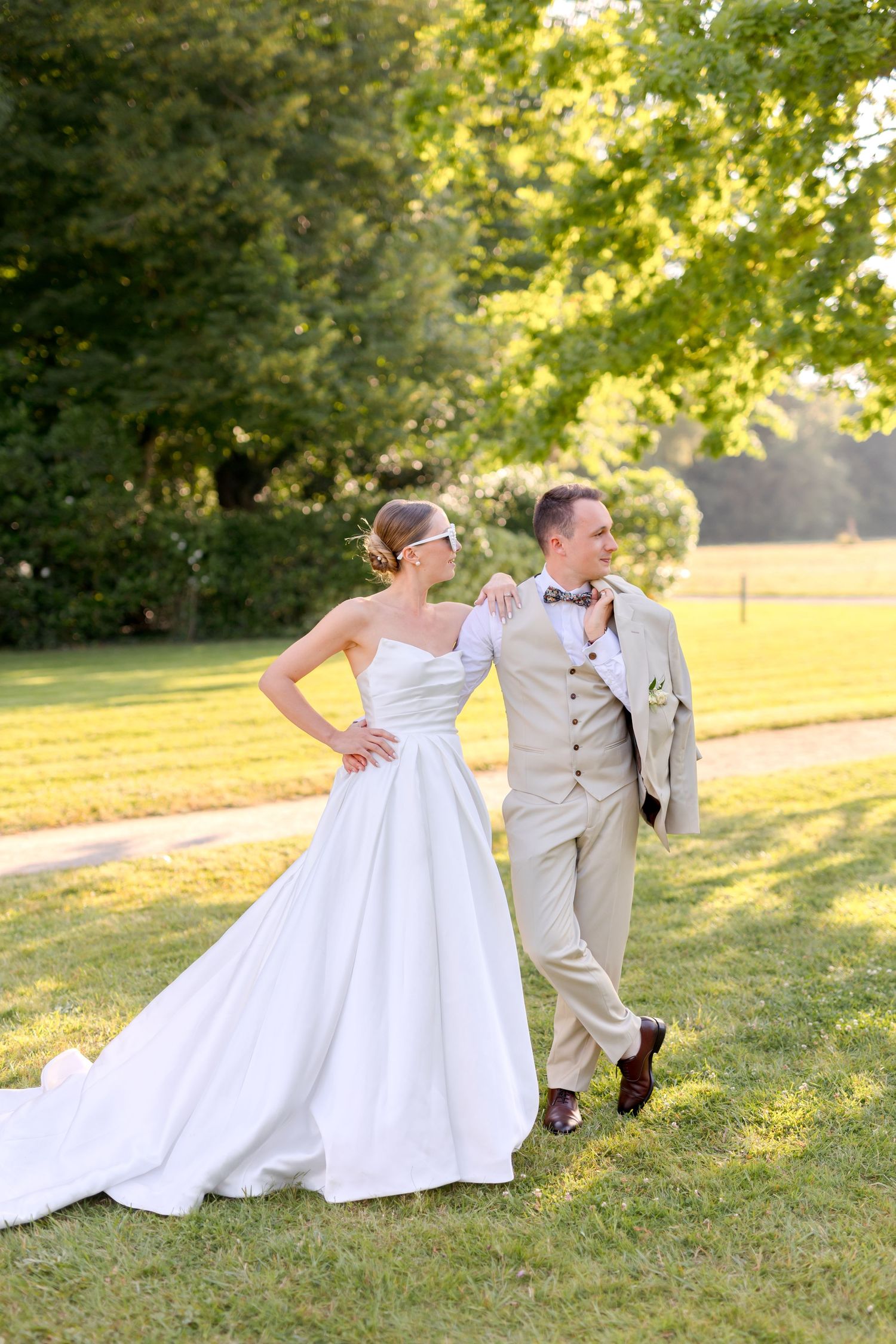 Couple poses playfully on grassy hillside during wedding photoshoot.