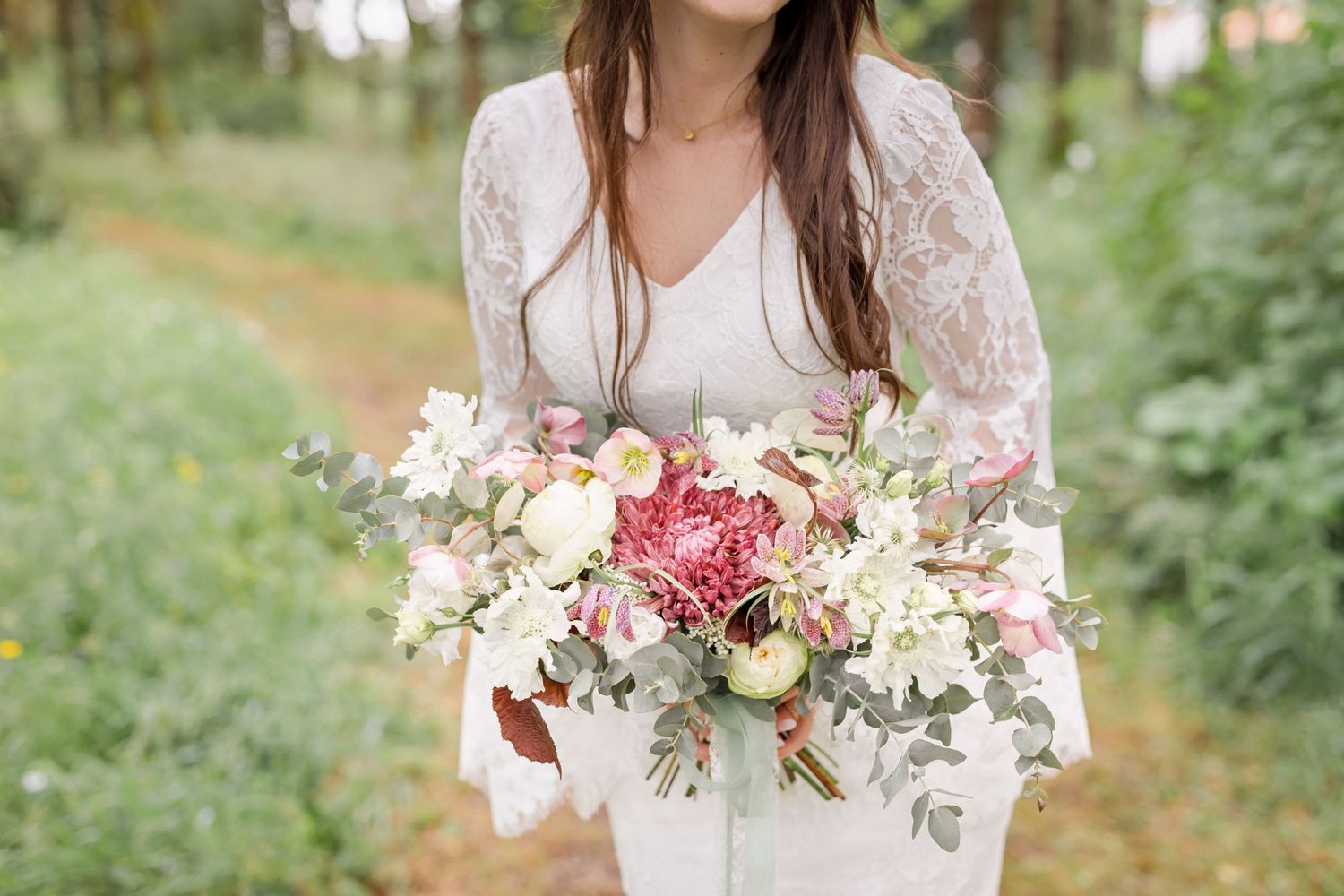 Bride holds a beautiful pink and white floral bouquet against her white lace wedding dress.