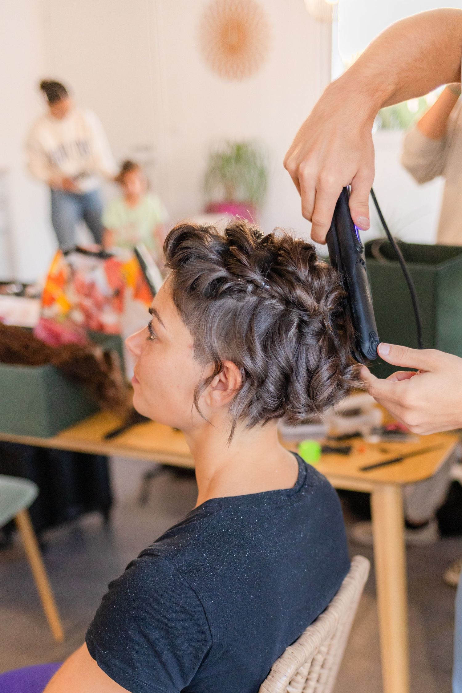 Hairstylist working on short pixie cut with clippers in salon setting.