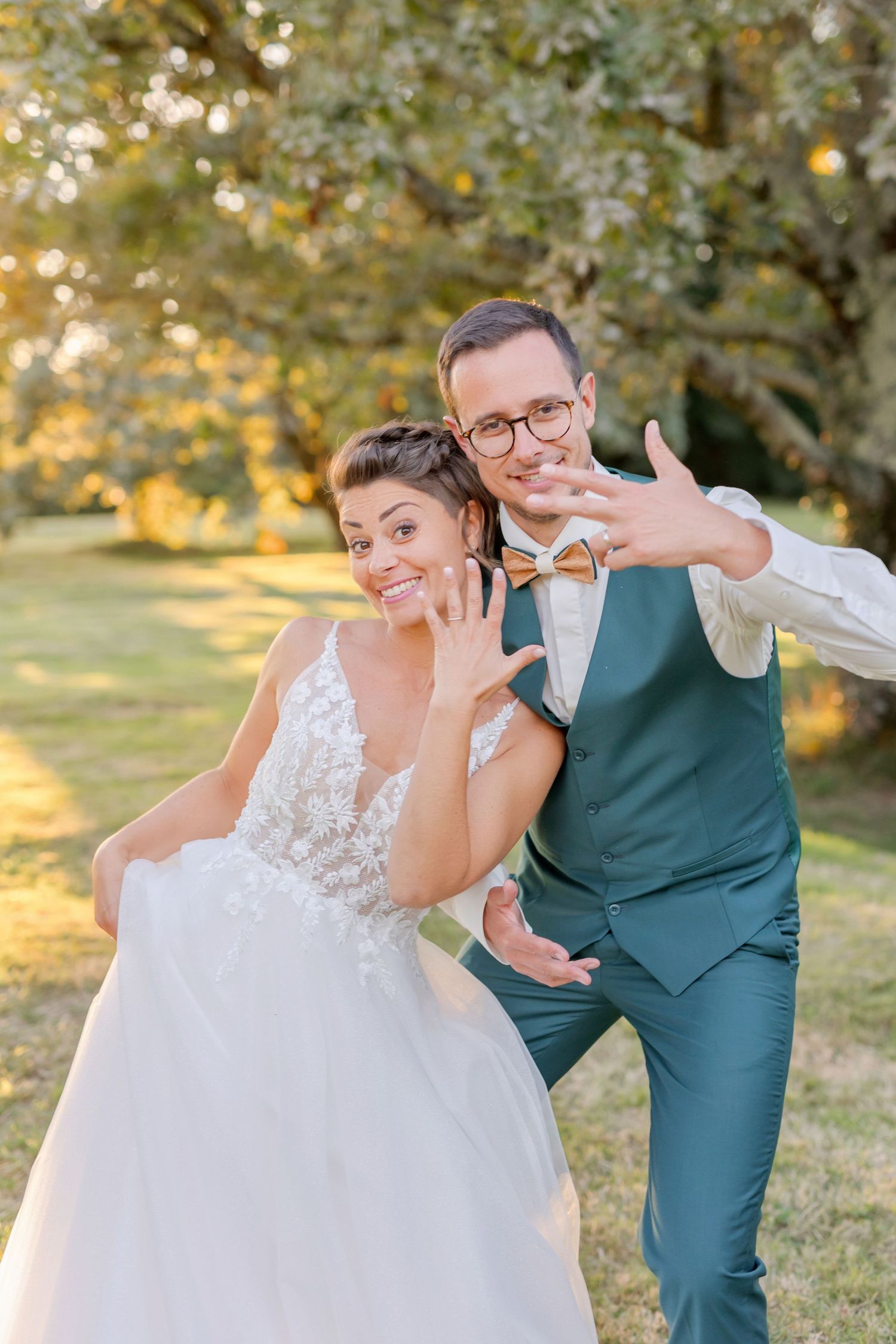 Fun wedding photo showing couple making silly faces and poses in garden setting during golden hour.