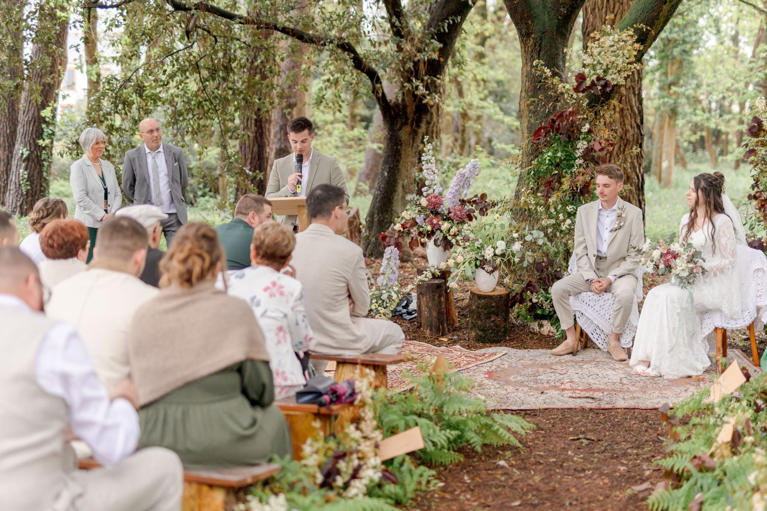 Panoramic view of guests seated along wooded path for outdoor ceremony.