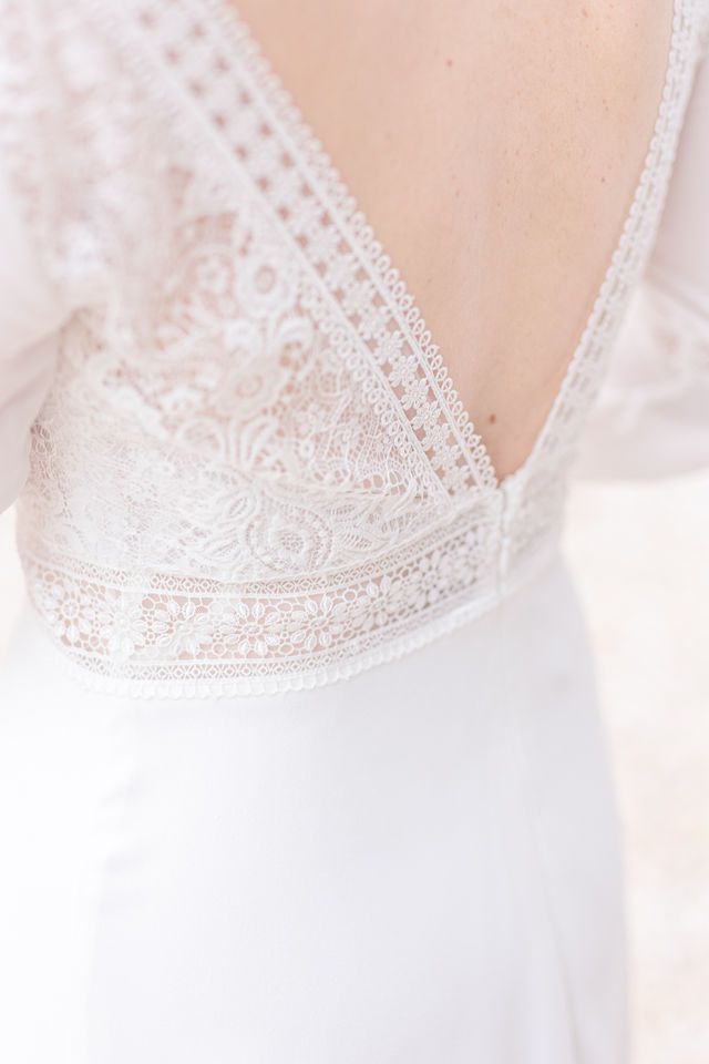 Elegant lace trim detail on white wedding dress bodice.