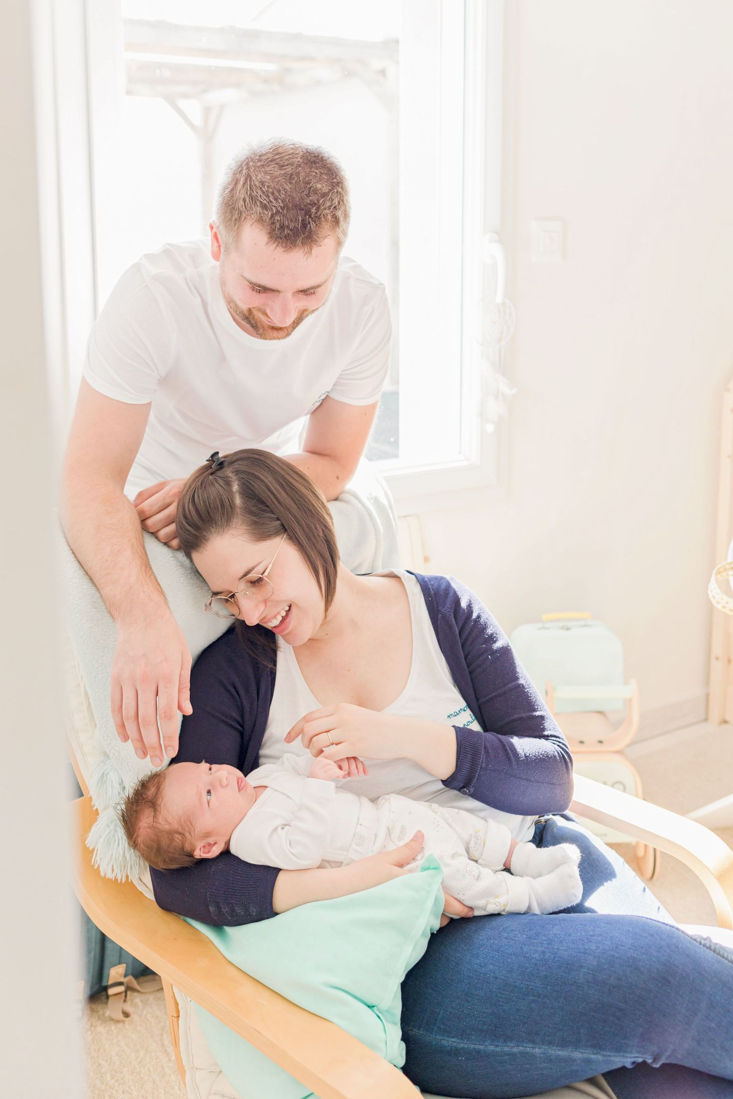 Parents sharing joyful moment with baby on mint green changing pad.