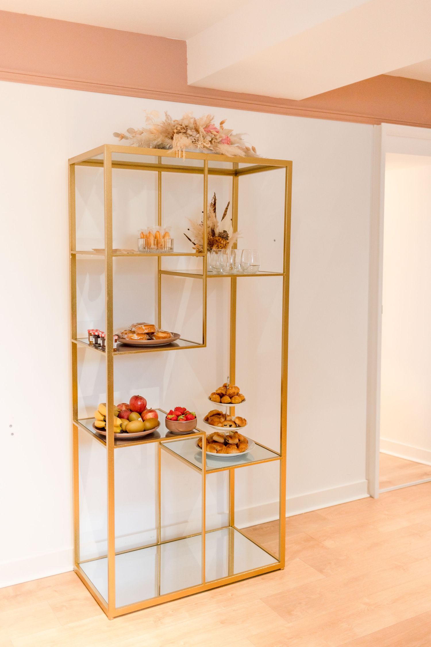 Gold modern display shelf with snacks and treats arranged on multiple levels.