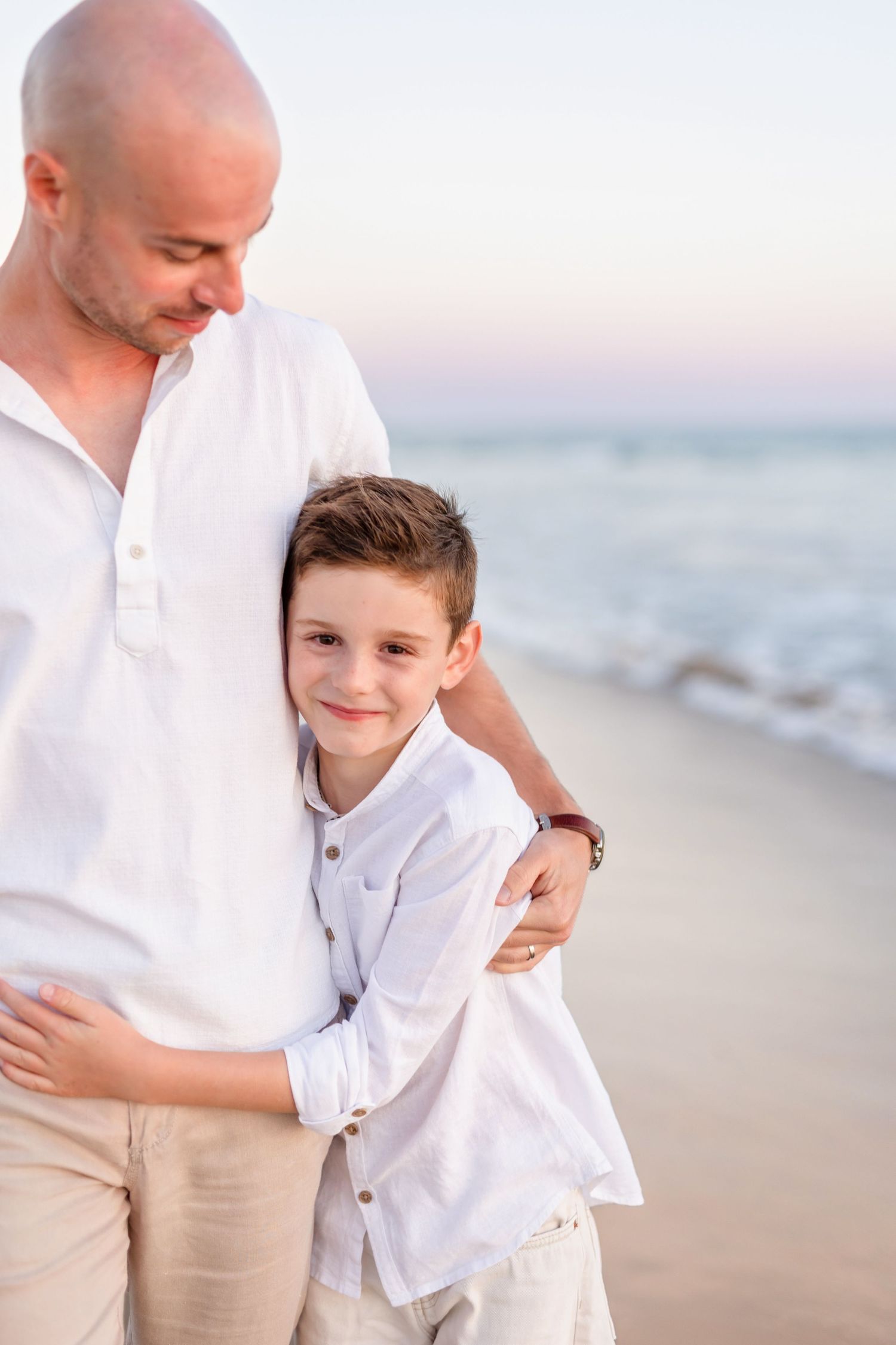 Tender moment captured between parent and child on a serene beach at sunset.