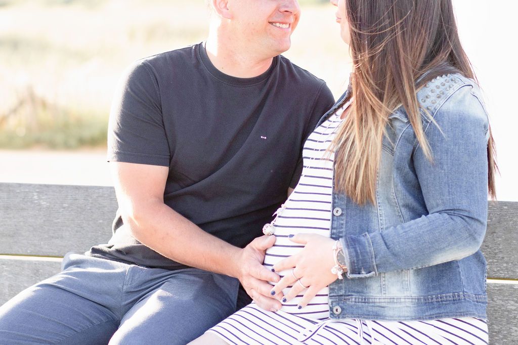 Close-up of expecting couple sharing intimate moment during coastal photoshoot.
