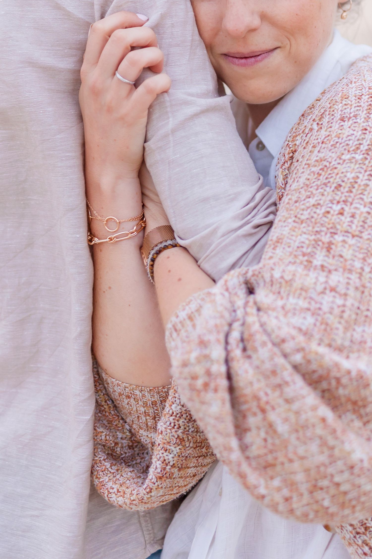 Close-up shot showing tender embrace and delicate jewelry details.