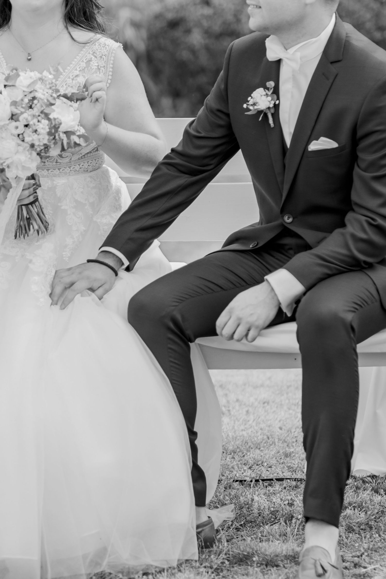 Black and white detail shot of couple sitting together in wedding attire.