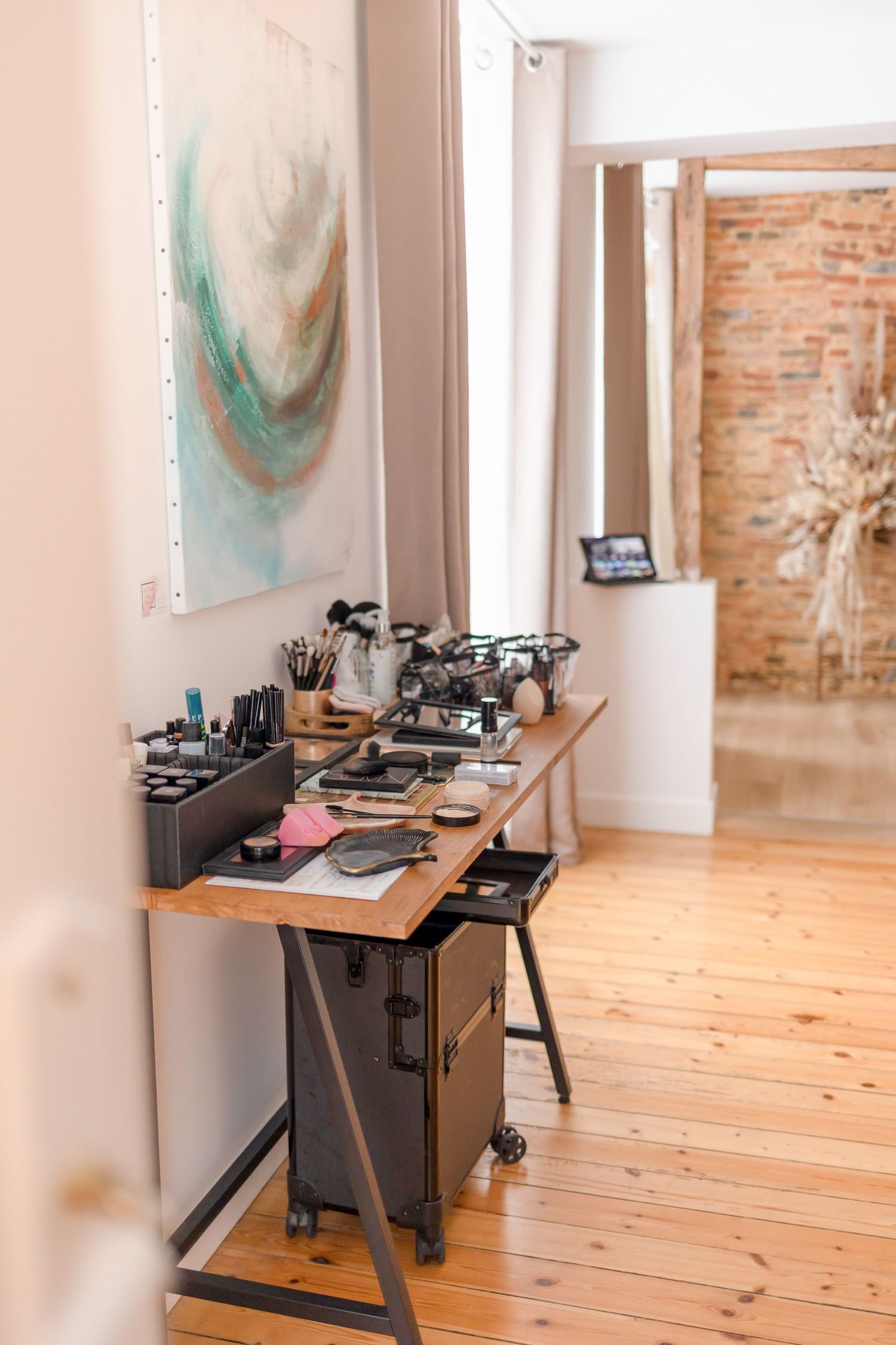 Vintage sewing machines arranged in a row on wooden tables in a brick-walled studio space.