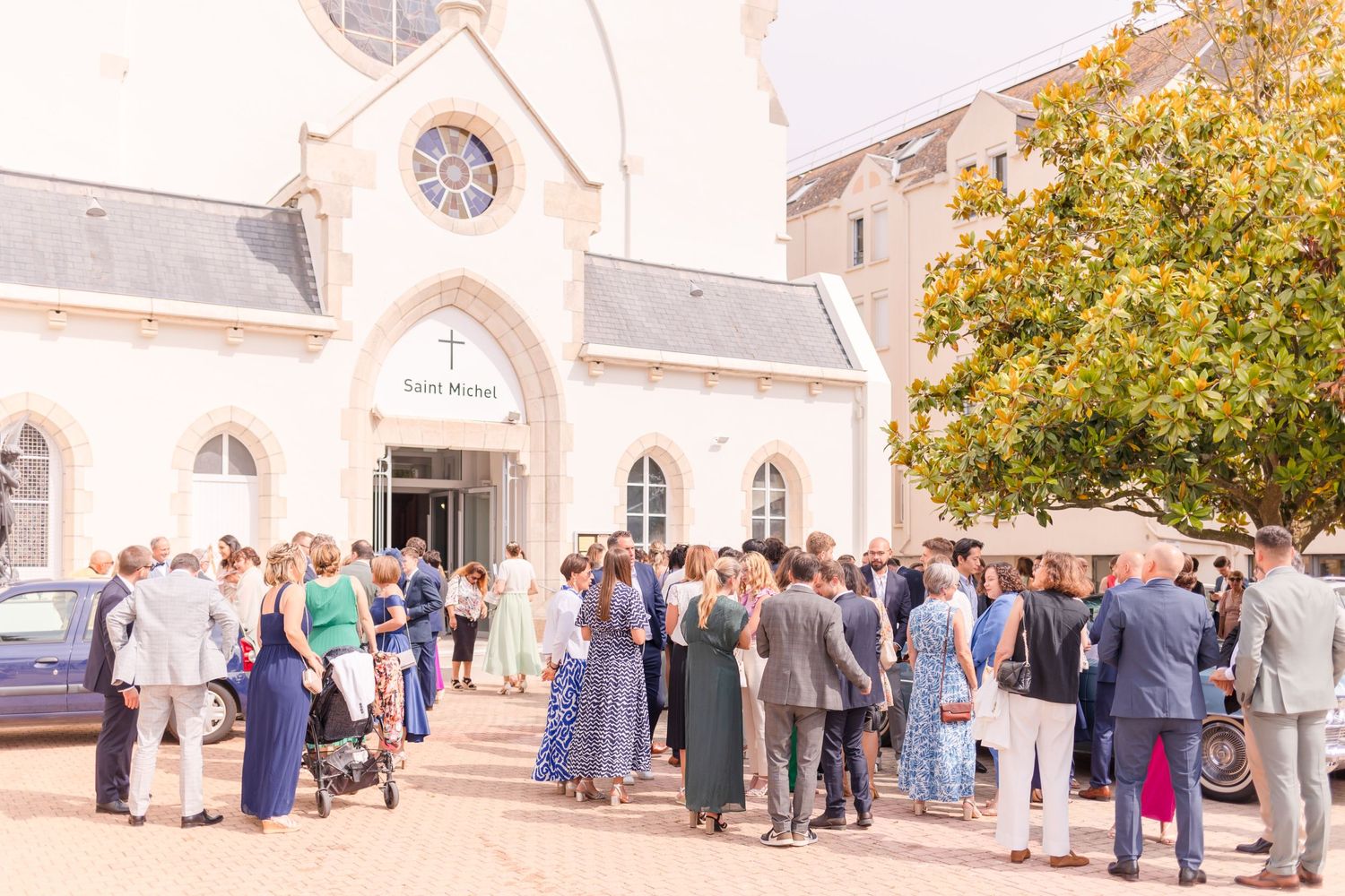 Guests gather outside a traditional stone church building for a wedding ceremony.