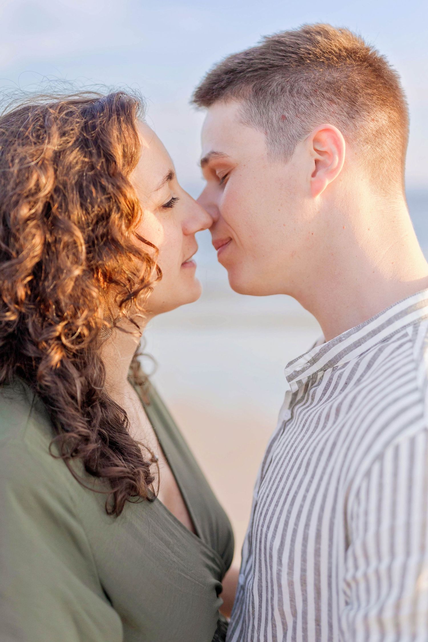An intimate moment between a couple as they share a close embrace on the beach at sunset.