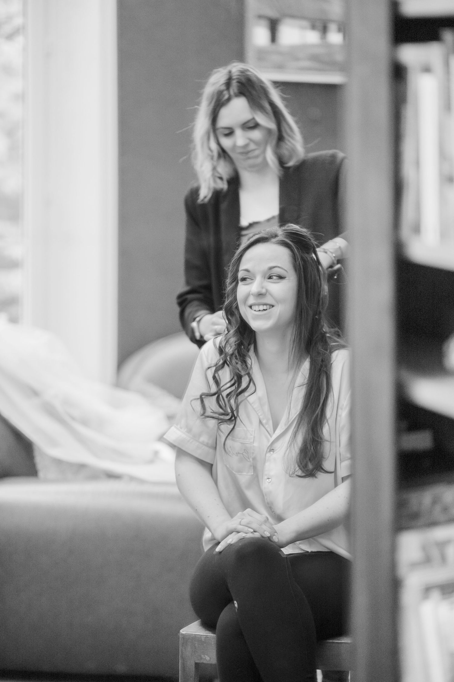 Black and white image of a hair styling session in a salon setting.