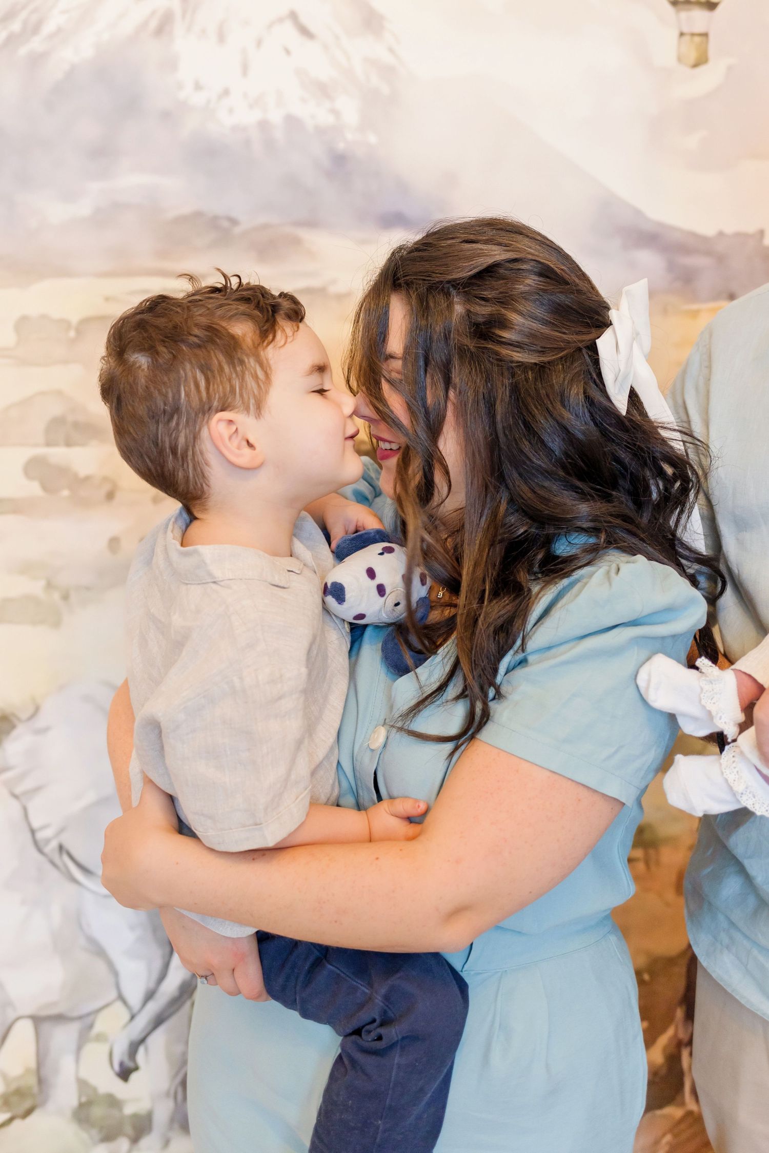Tender family moment against mountain mural backdrop in nursery setting.