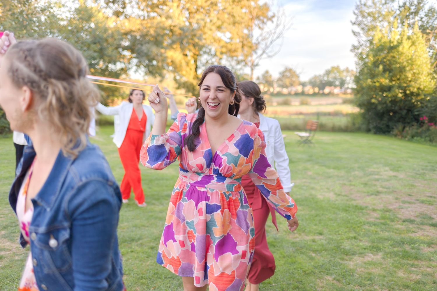 Outdoor wedding celebration with guests enjoying festivities in a natural autumn setting.