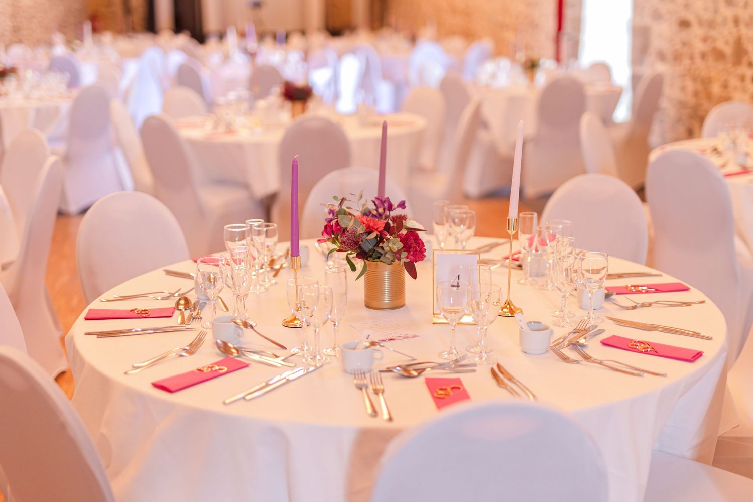 Wedding reception table setup with white linens, pink accents, and fresh floral centerpieces.