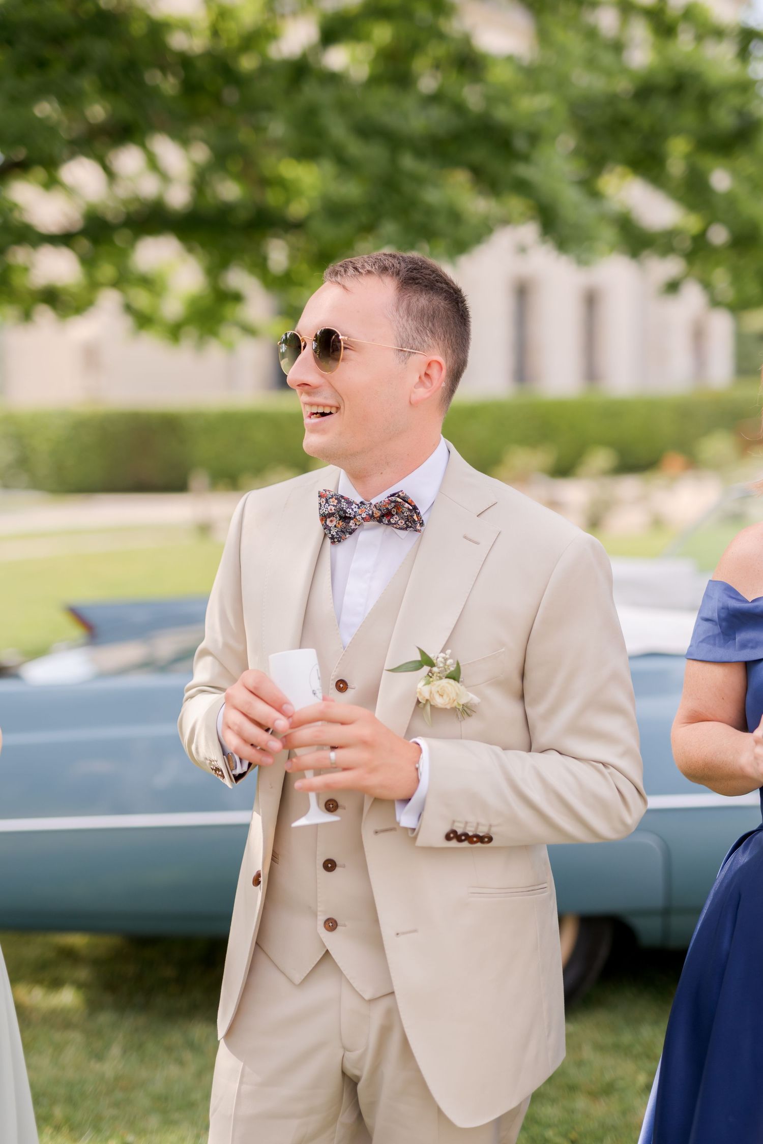 Guest in beige suit and bowtie enjoying outdoor wedding reception.