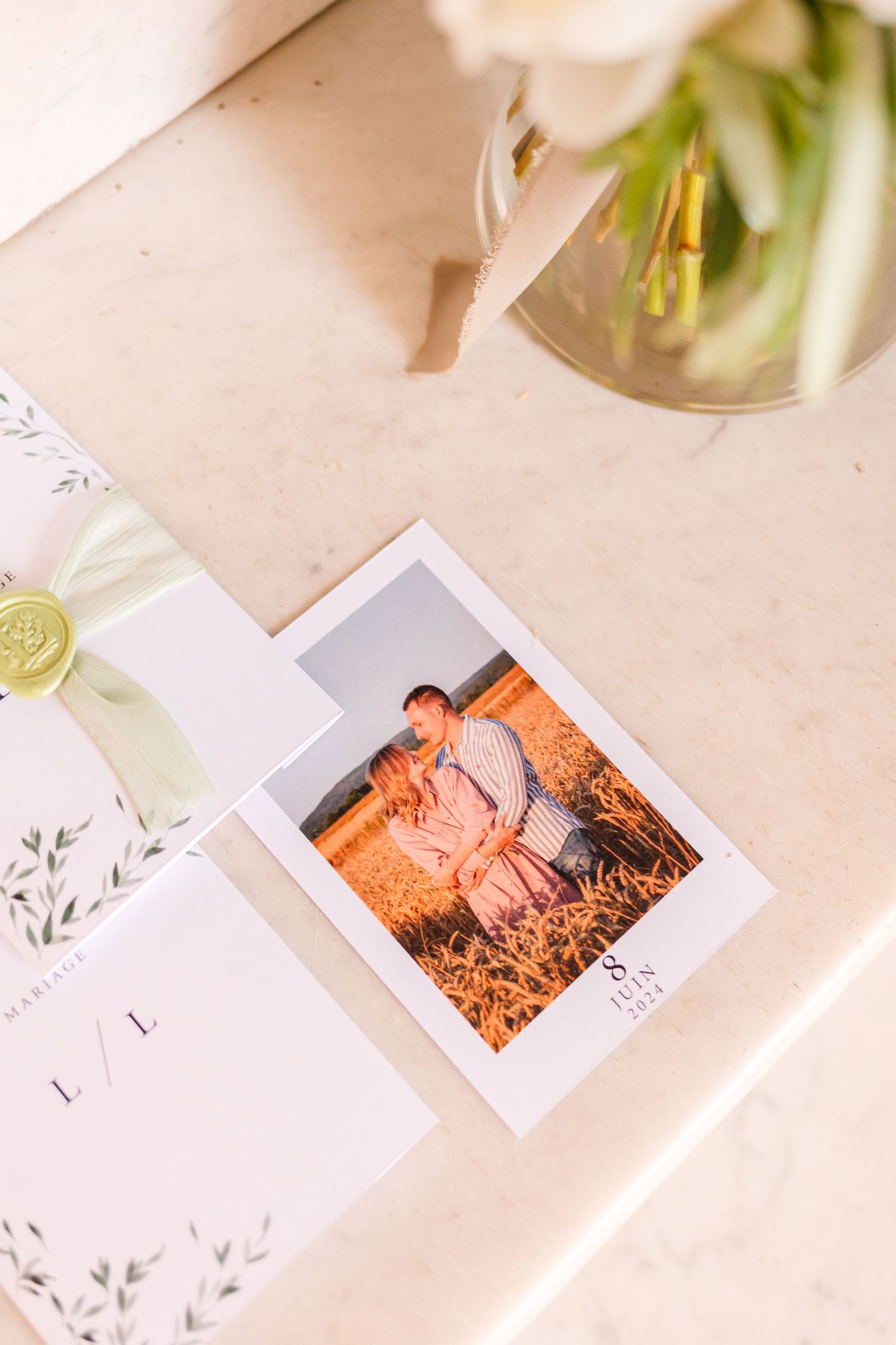 Wedding photographs and cards displayed with white flowers on a beige surface.