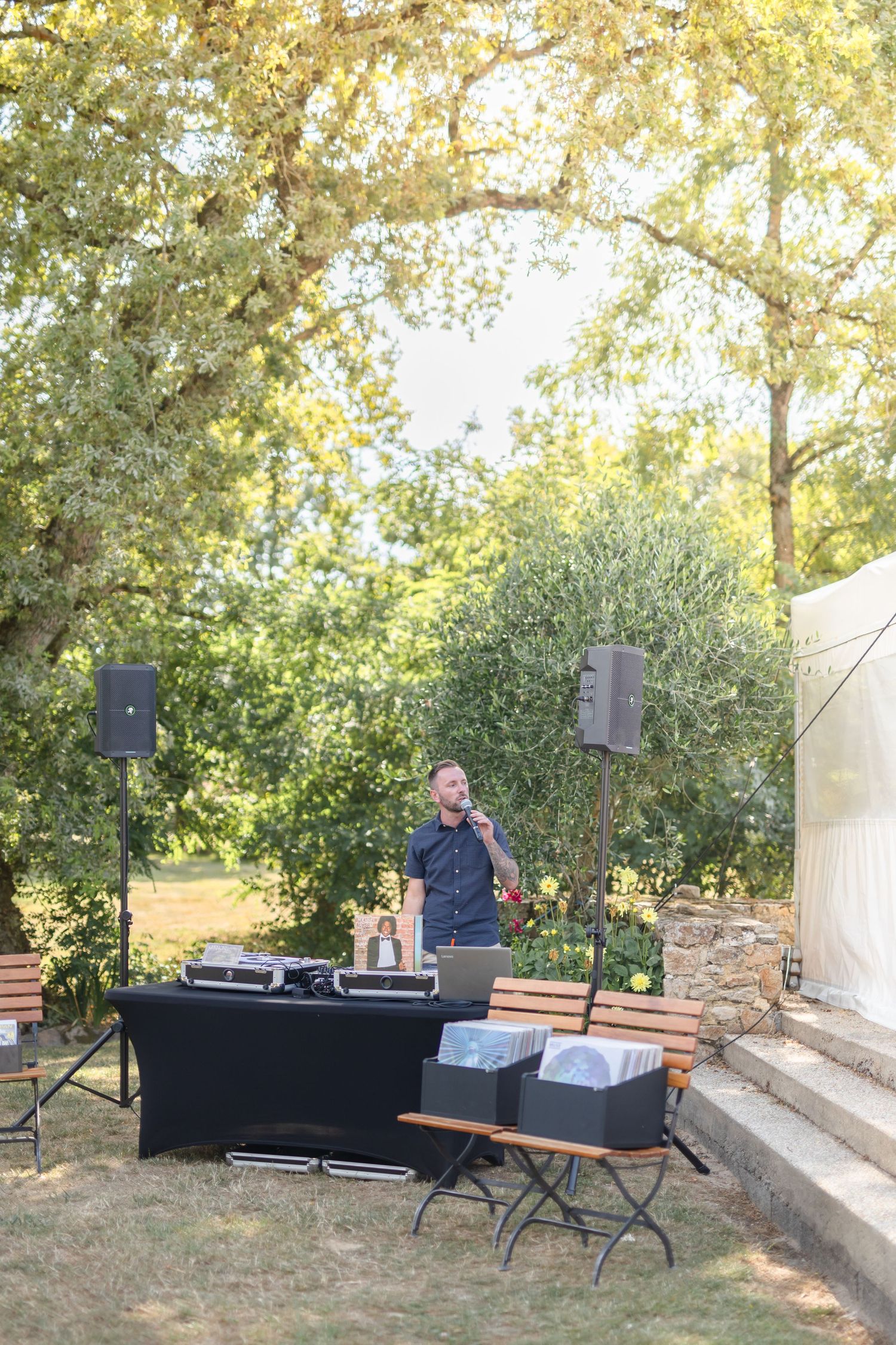 DJ setup with speakers and equipment in an outdoor garden setting.