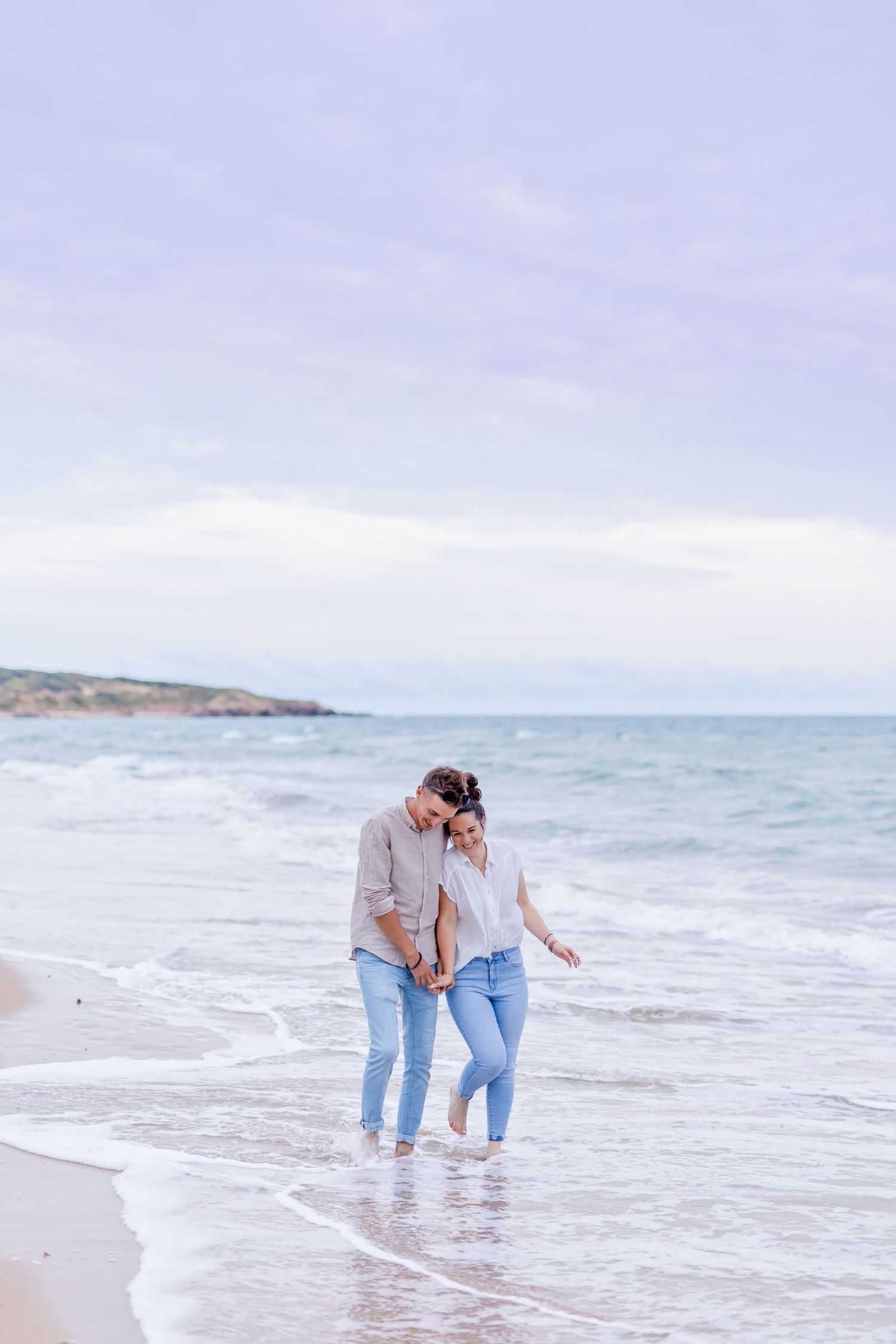 Two people enjoying romantic moment while walking in ocean surf.