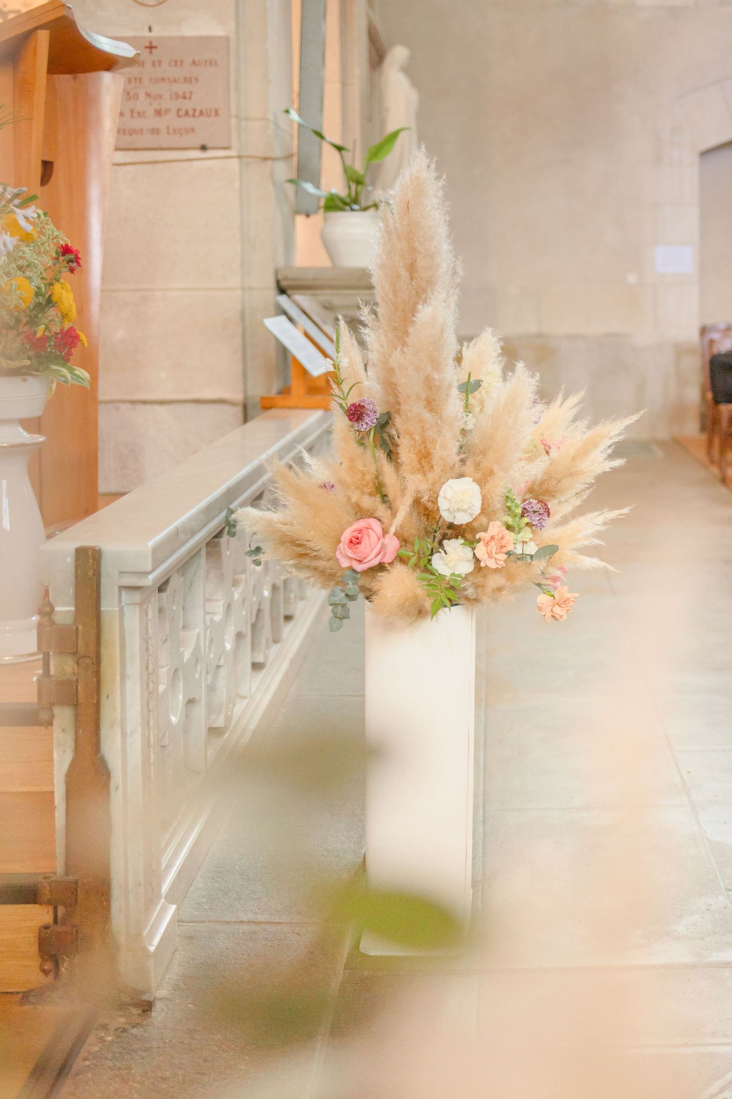 Romantic dried pampas grass and pink rose floral arrangement in a church setting.