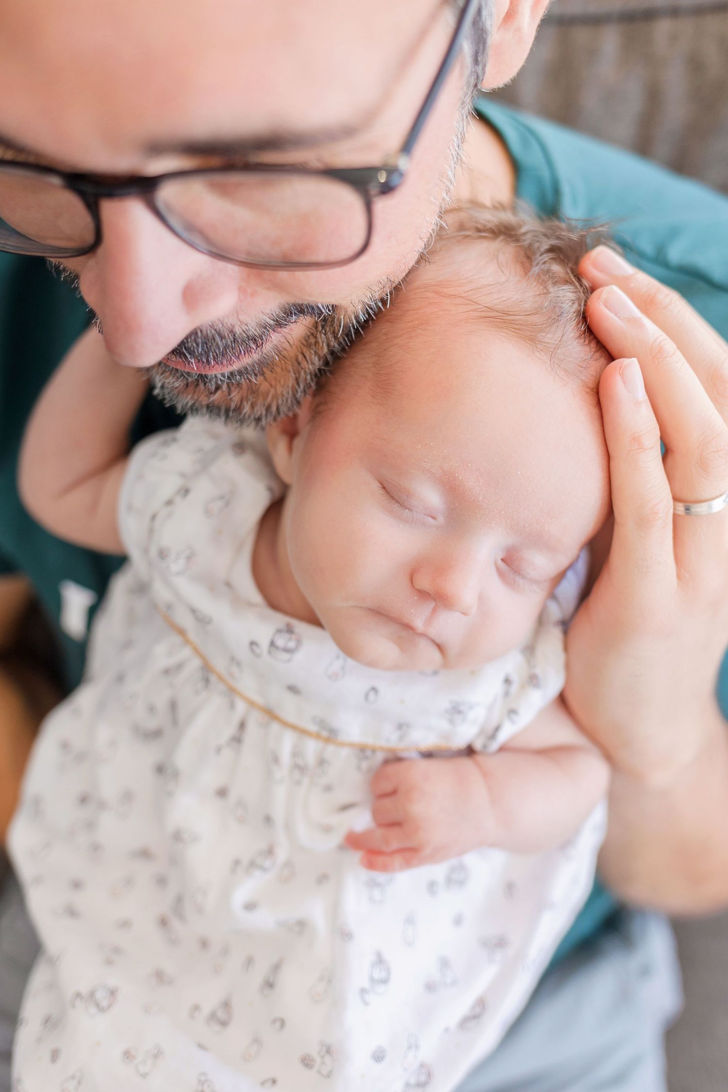 Close-up of sleeping baby in patterned outfit being tenderly held.