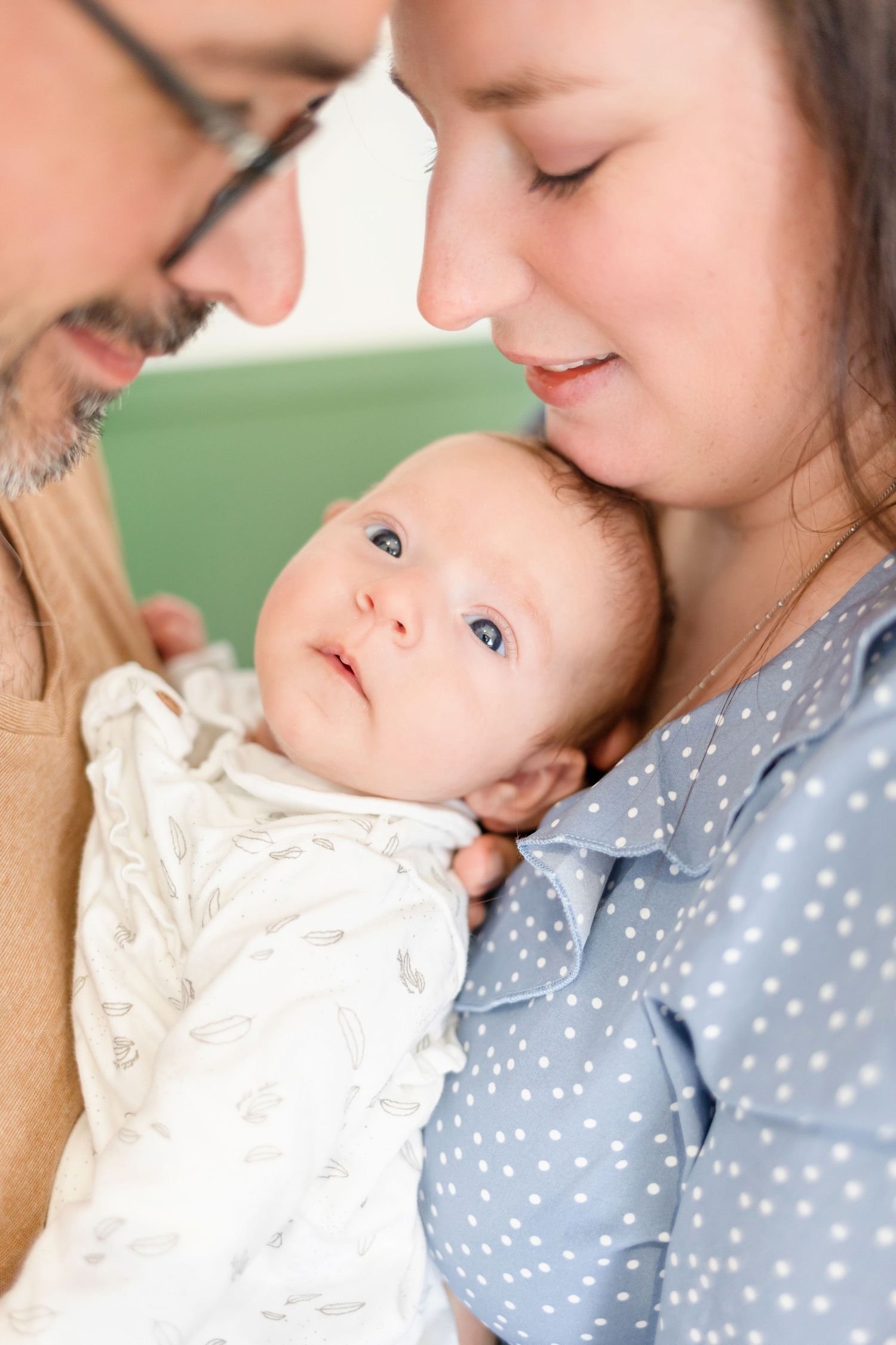 Intimate family moment captured in nursery with sage green walls.