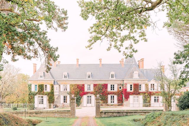 Elegant stone mansion with red ivy and classic architecture under autumn skies.