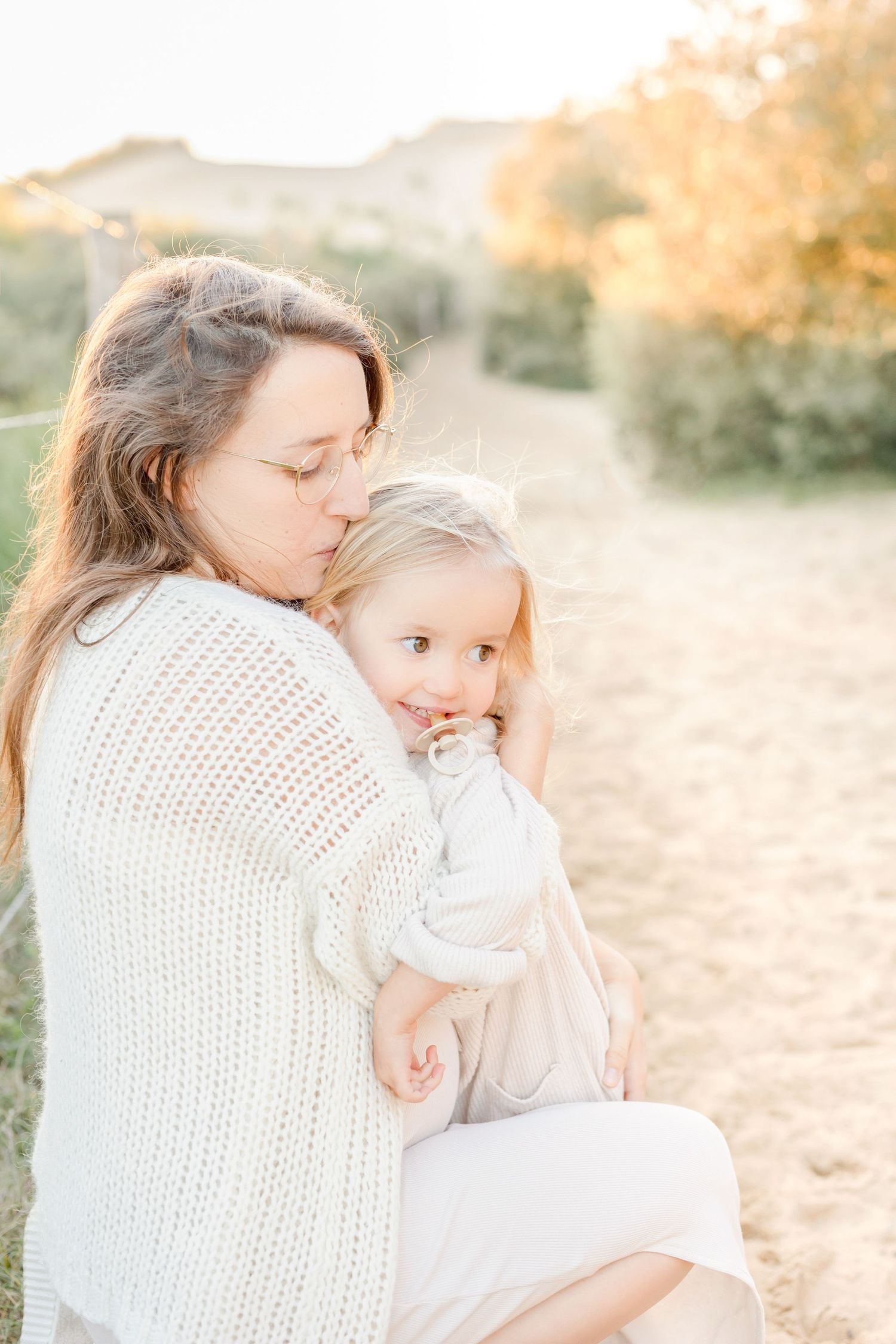 Tender moment between parent and child outdoors during sunset photoshoot.