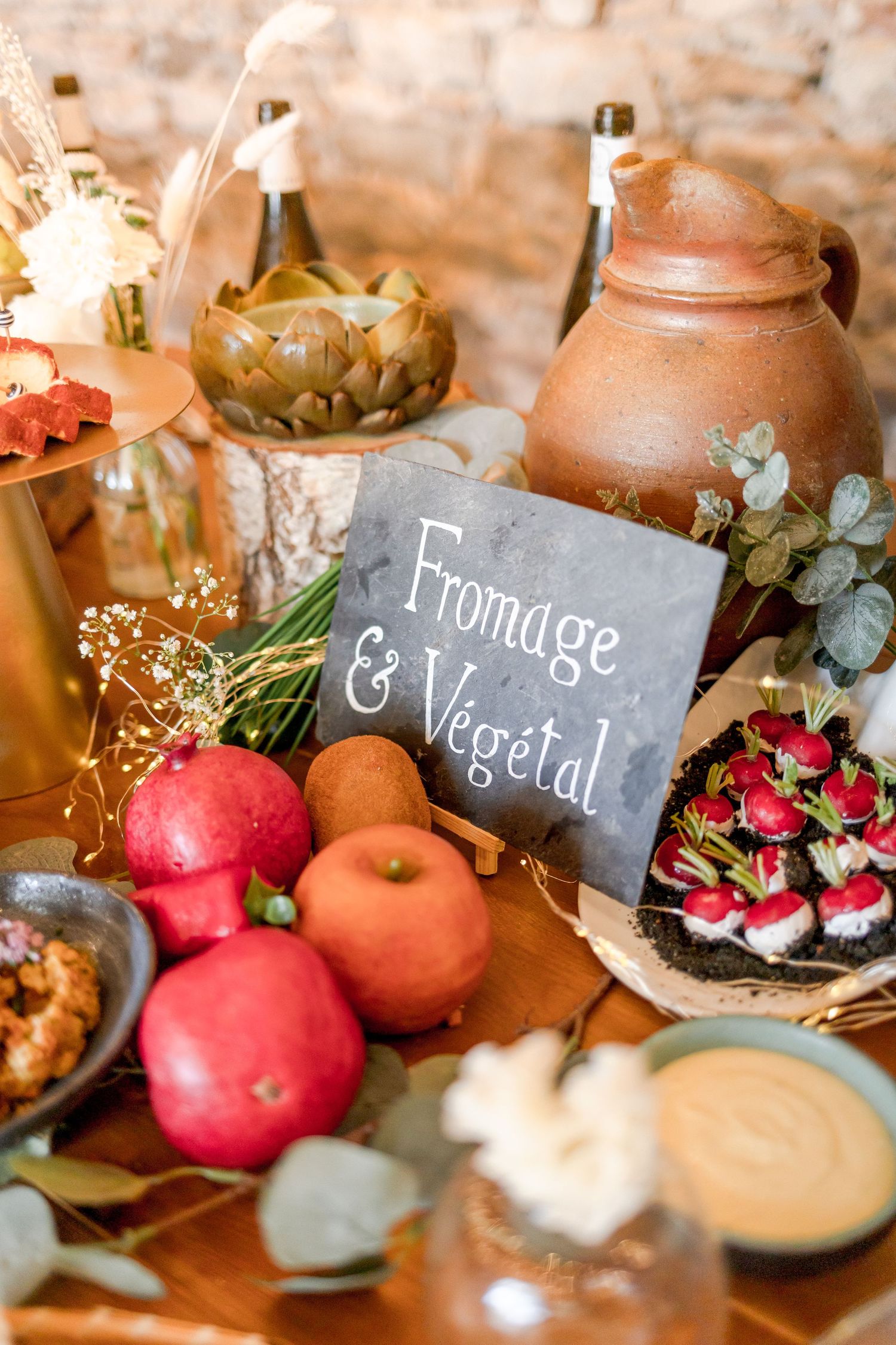 French-style food display with 'Fromage & Vegetal' sign, fresh fruits, and earthenware pottery.