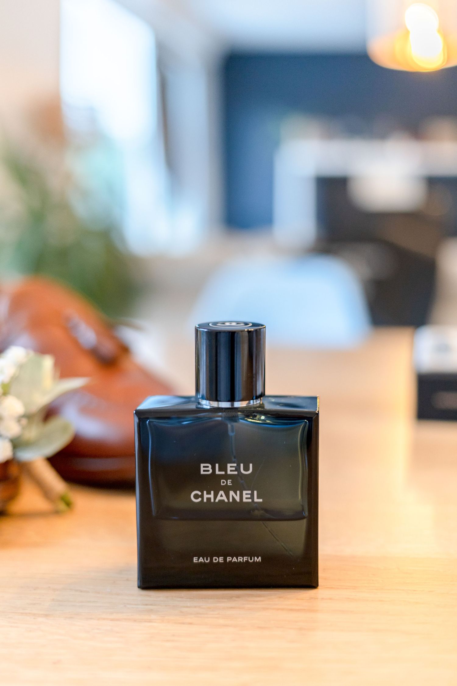 Bottle of Chanel Bleu perfume displayed on wooden surface.
