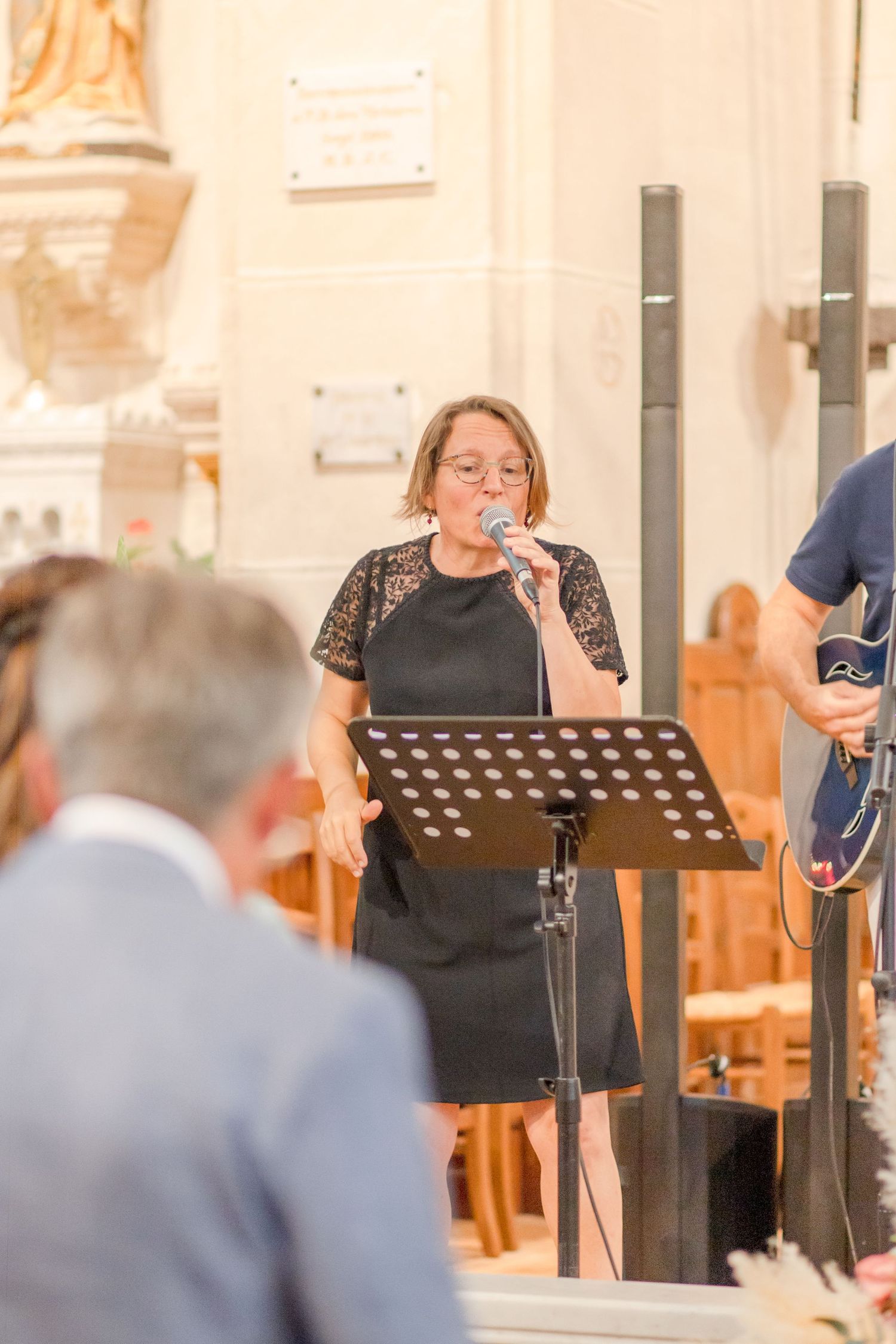 A vocalist performing at a music stand during a church ceremony.
