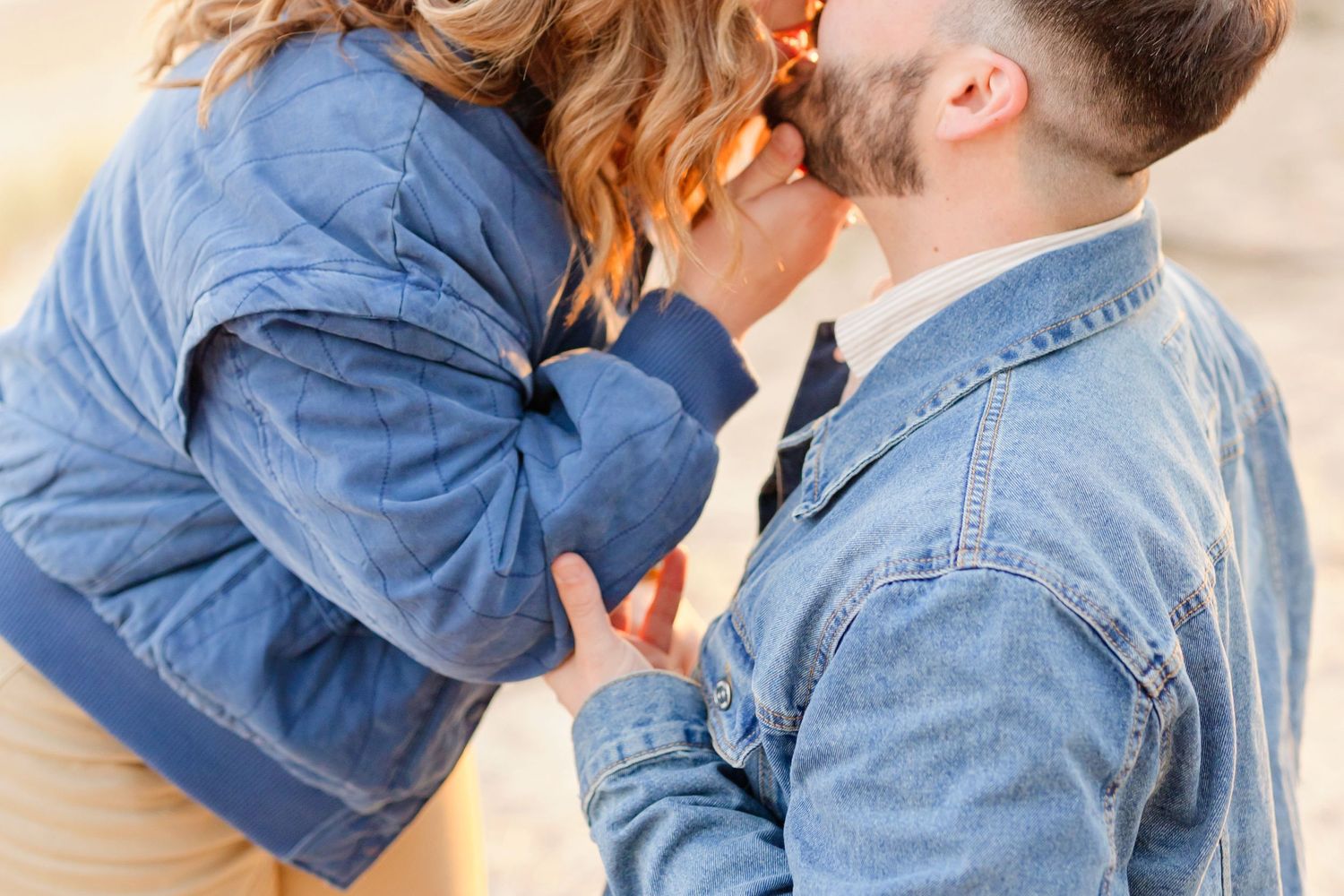 A tender embrace between two people wearing denim jackets in natural outdoor lighting.