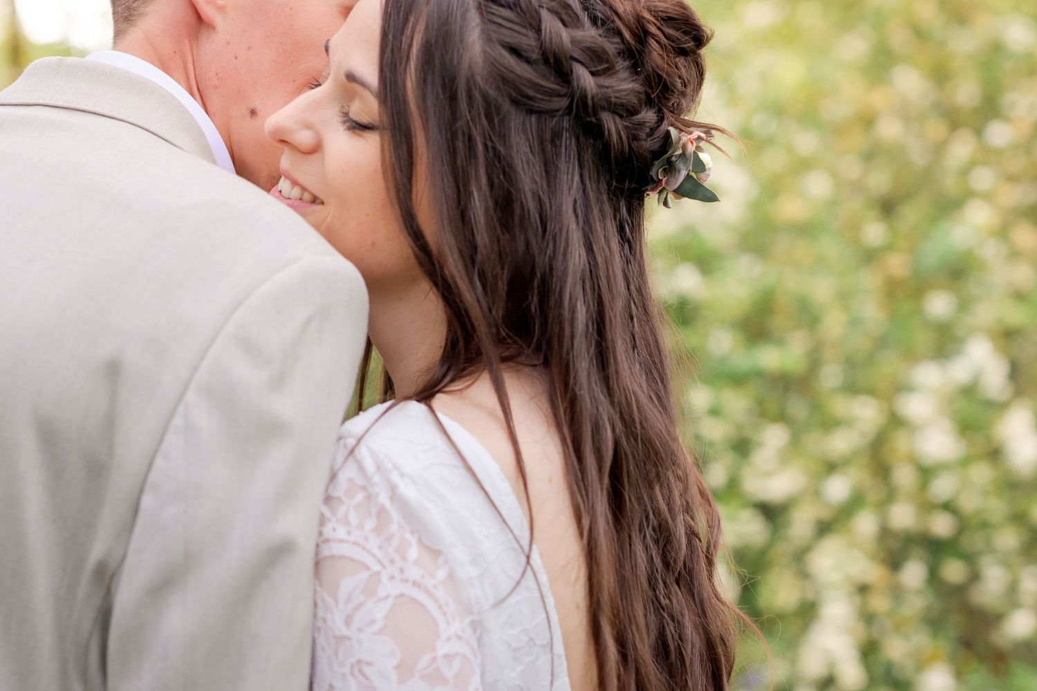 Close-up of a tender moment between newlyweds in a forest setting.