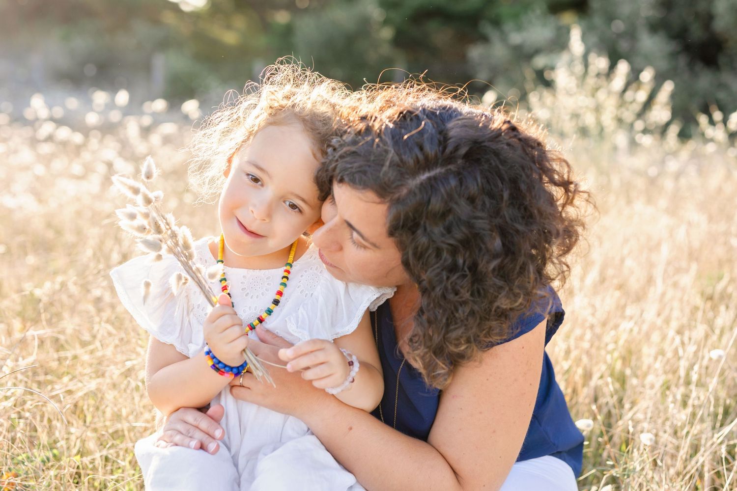 Joyful embrace between parent and child in sun-drenched meadow.