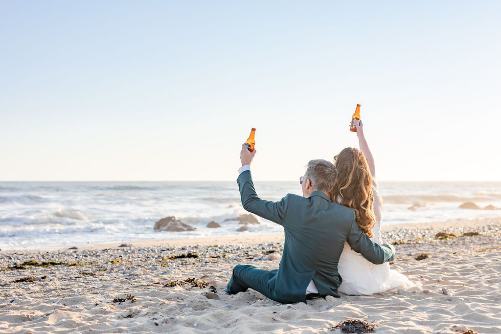 Wedding couple relaxing on beach sand during golden hour photoshoot.
