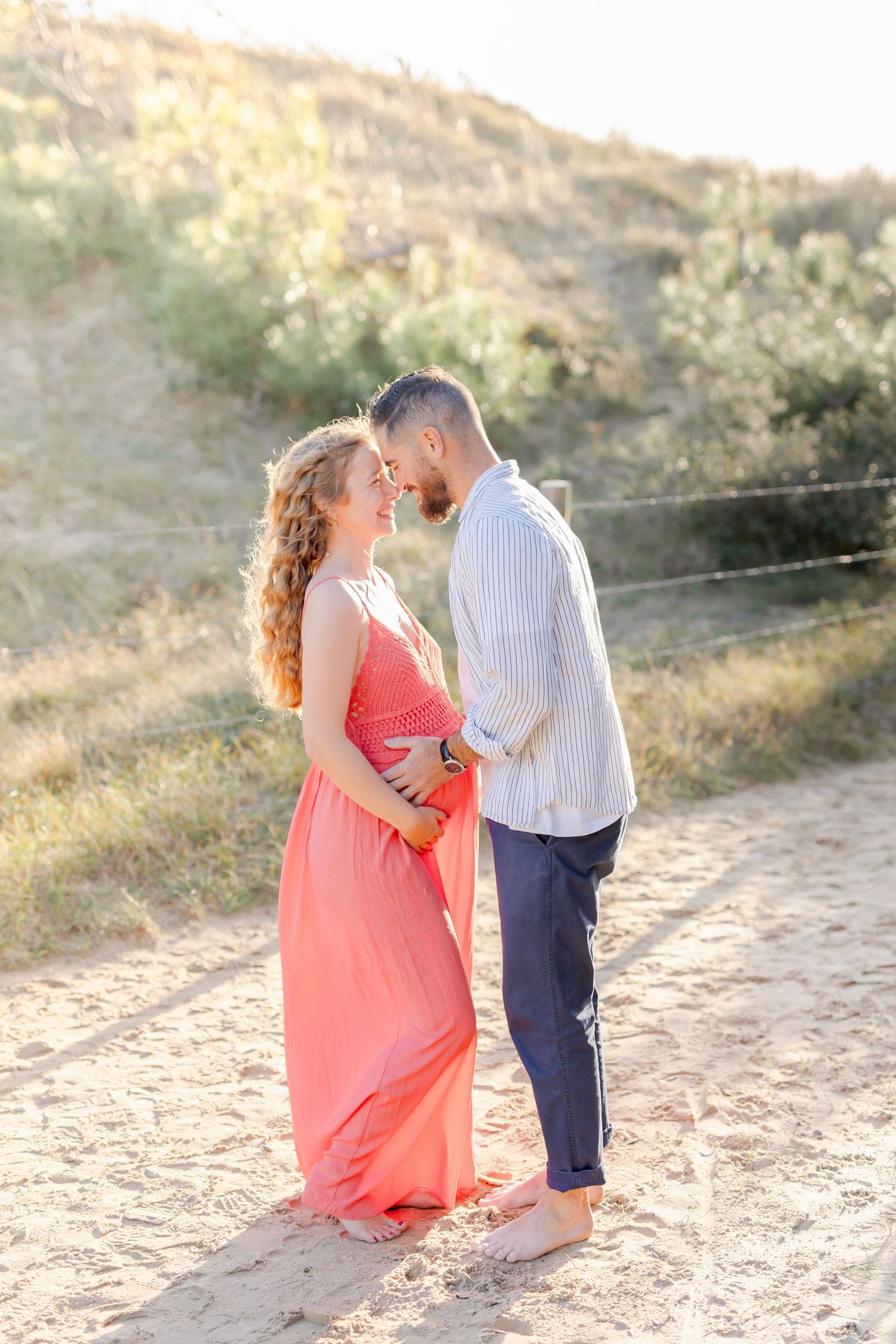 A romantic moment between a couple on a sunlit dirt path surrounded by nature.
