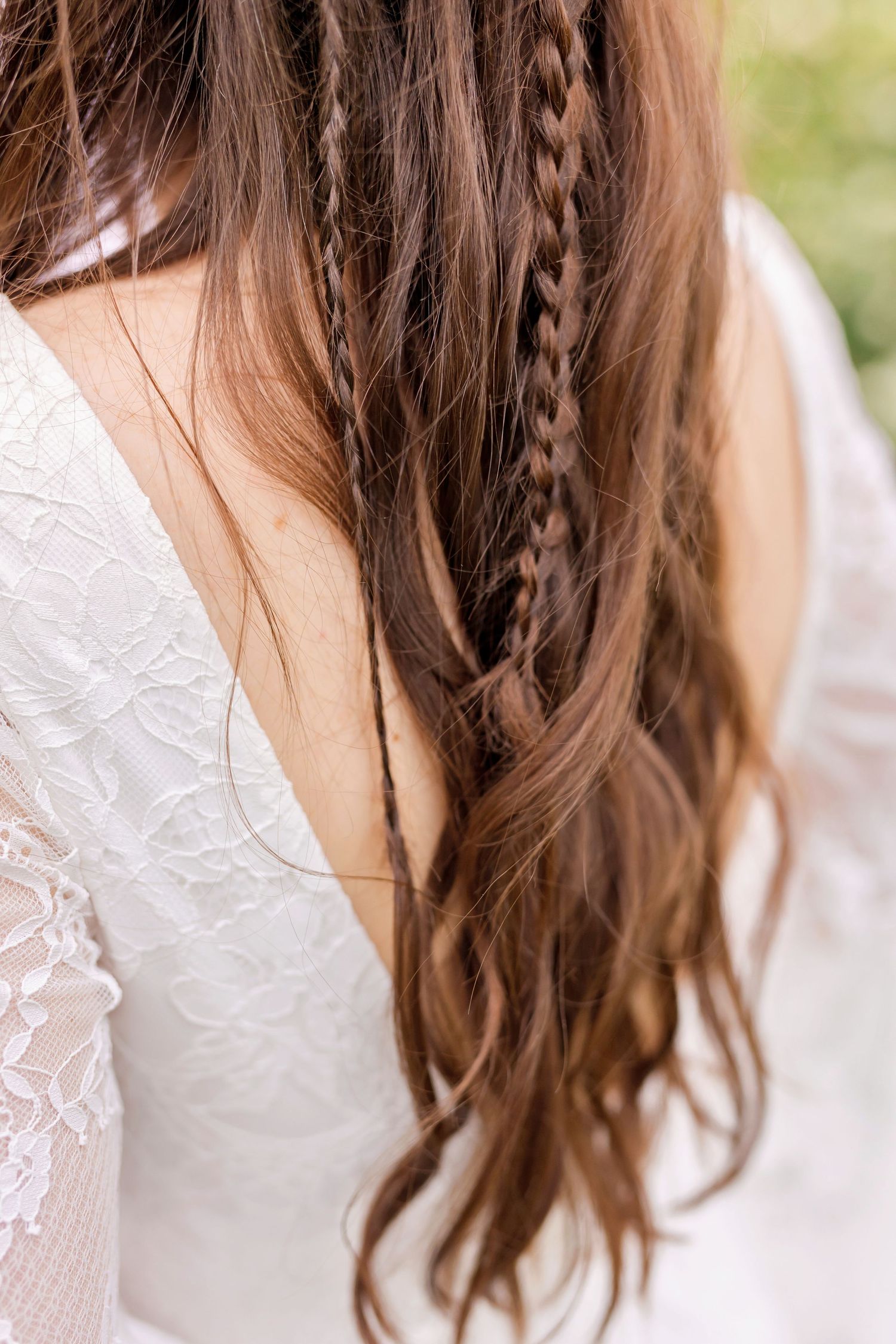 Long brunette hair with intricate braids and lace dress detail shown from behind.