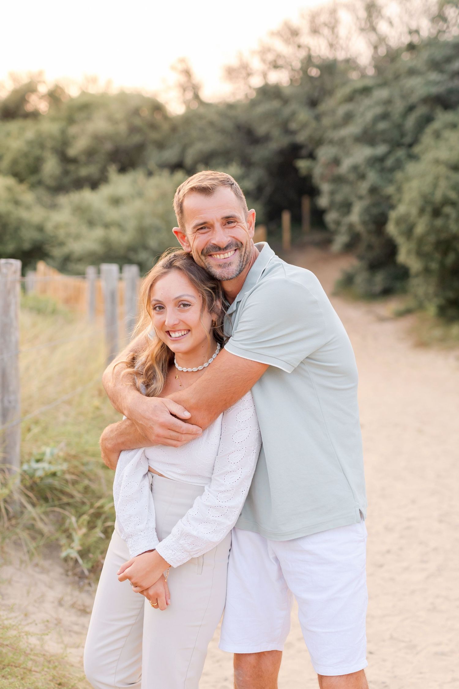 Two people embracing on a nature trail during golden hour.