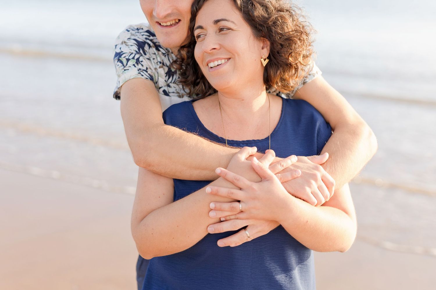 A tender embrace shared between a couple on a peaceful beach at sunset.
