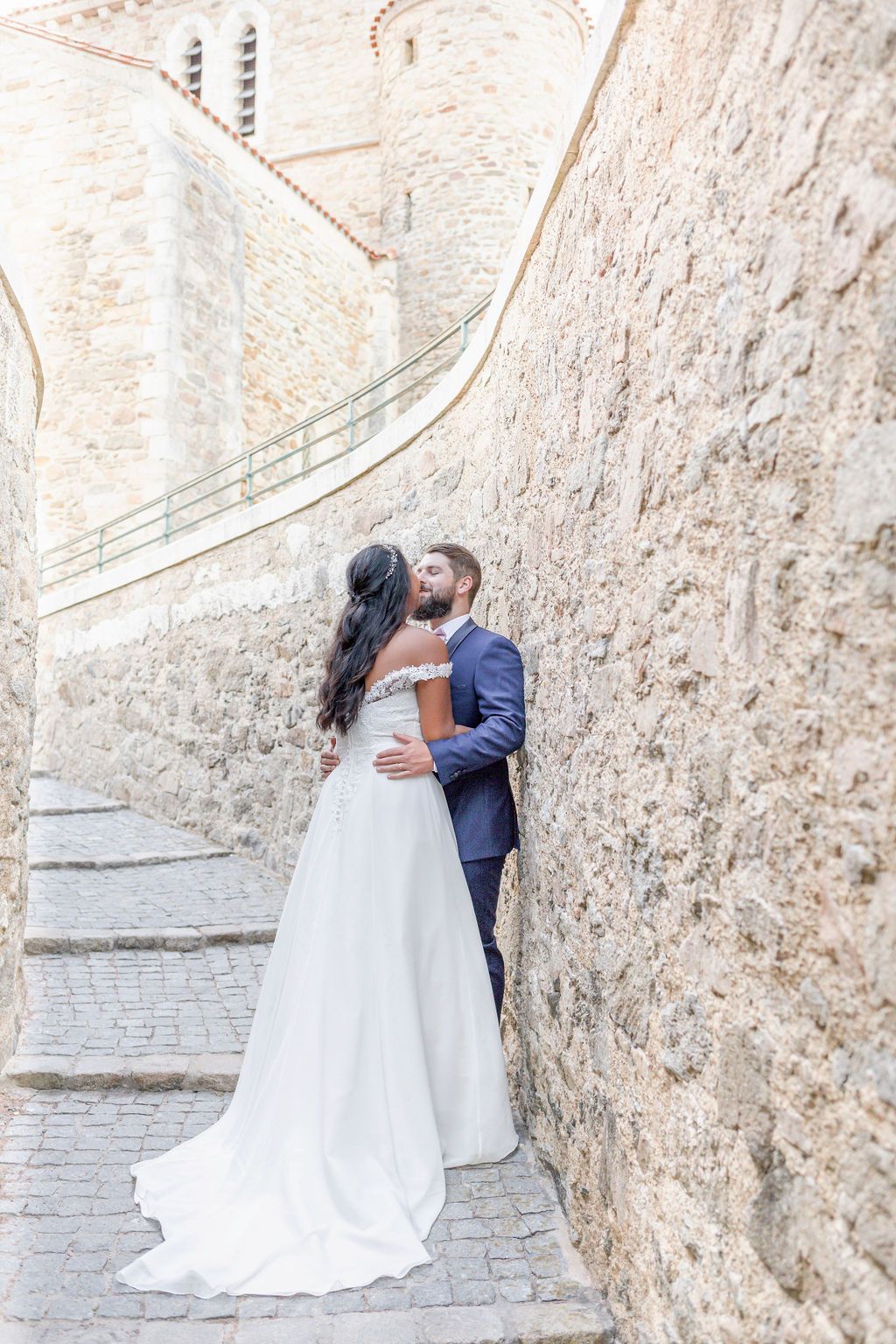 Romantic moment captured on ancient stone steps with rustic wall backdrop.