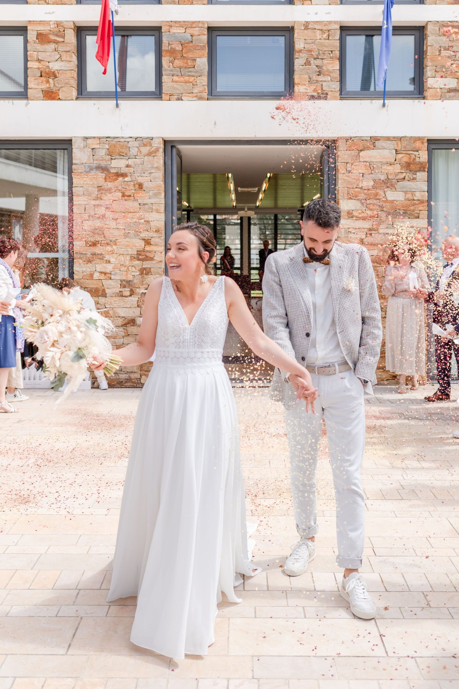 Wedding party members in white and light gray outfits posing outdoors.