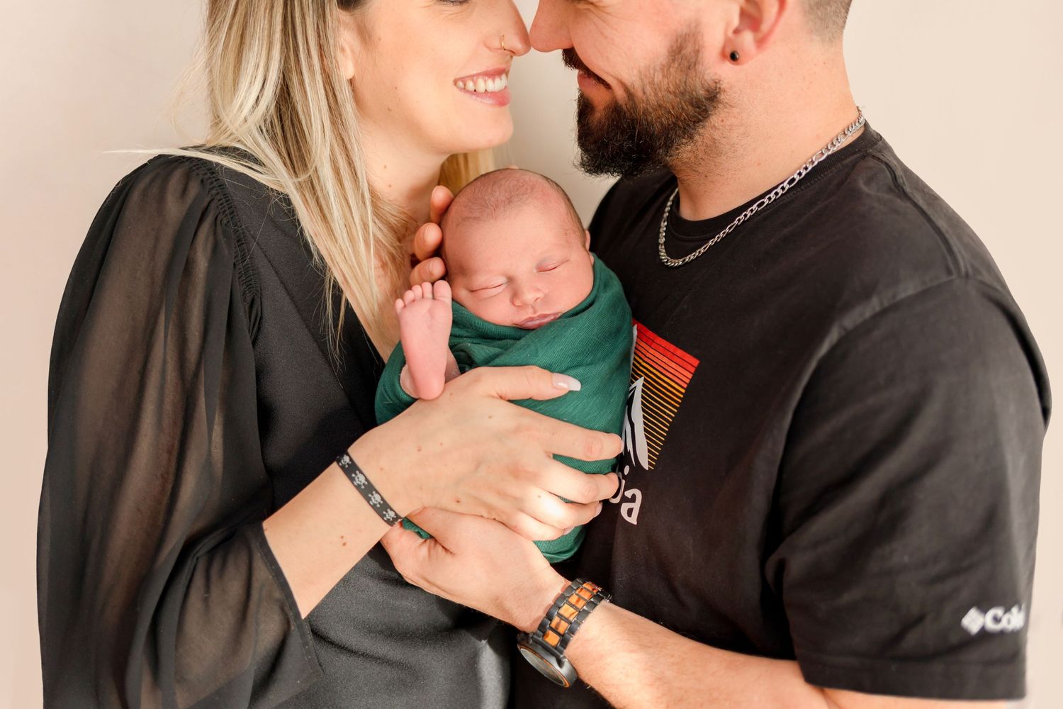 Sweet candid moment of parents smiling while holding their tiny baby.