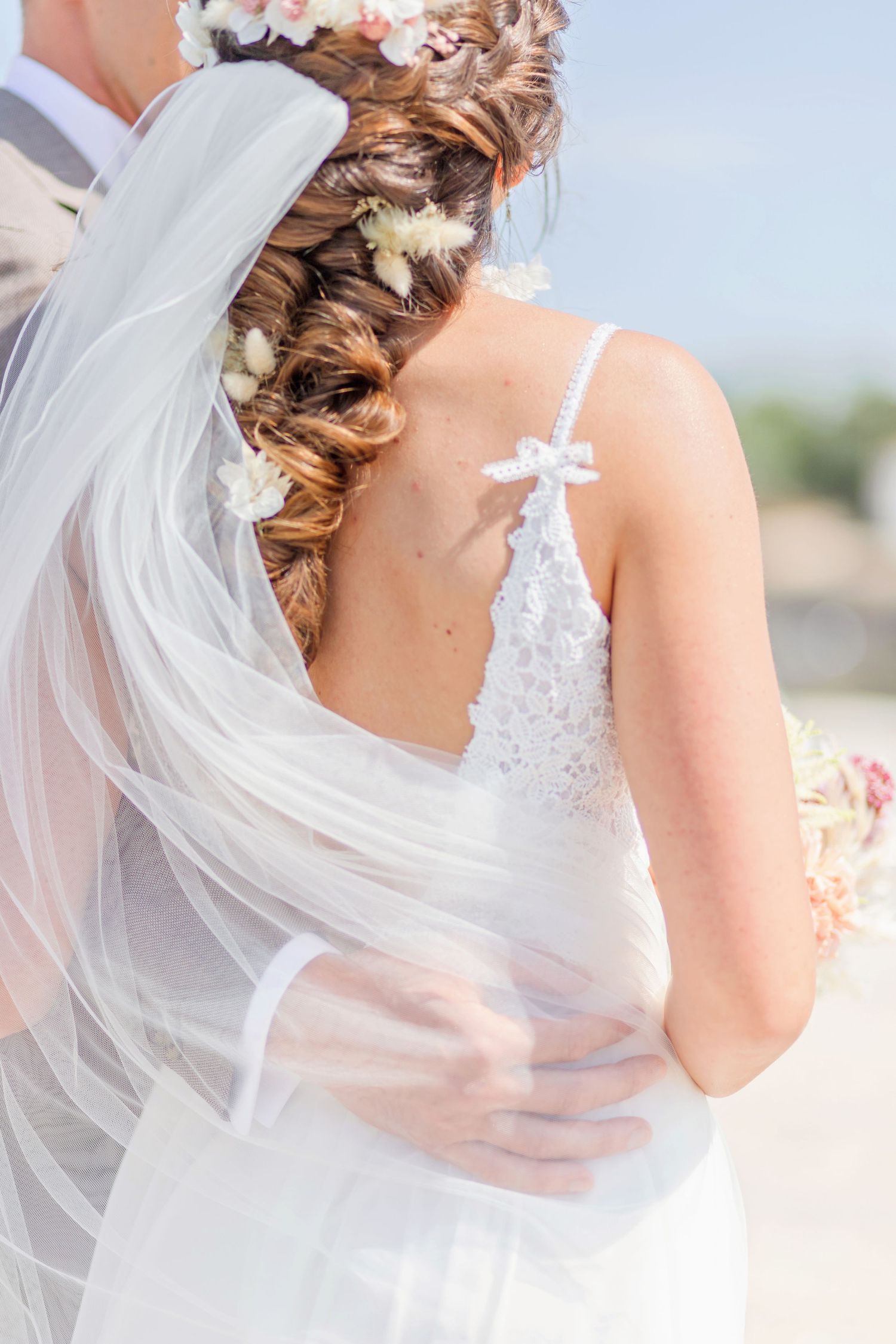 Close-up detail of bride's flowing veil and floral-adorned braided hairstyle.